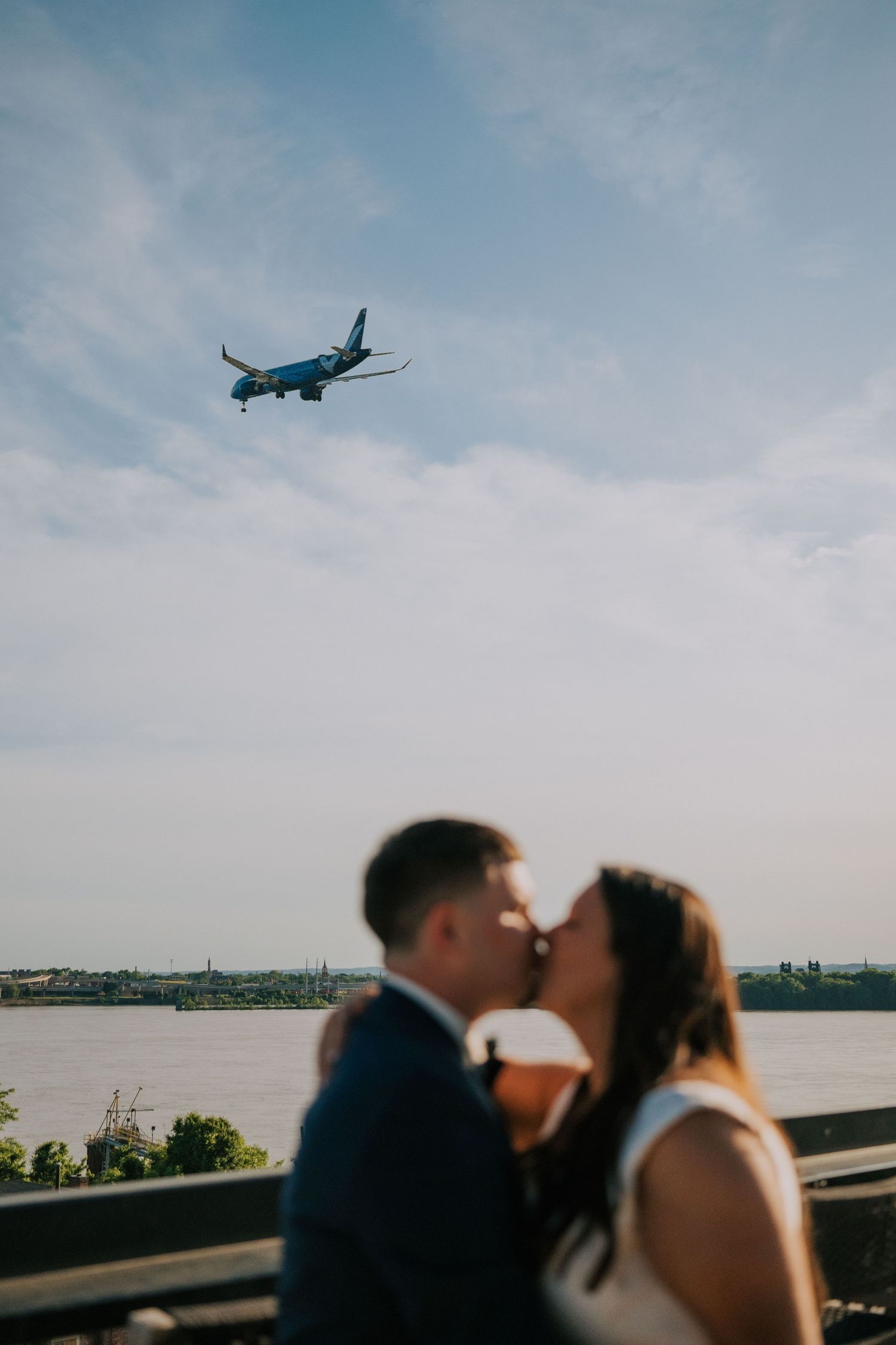 Airplane flies overhead during romantic rooftop wedding moment with city skyline.