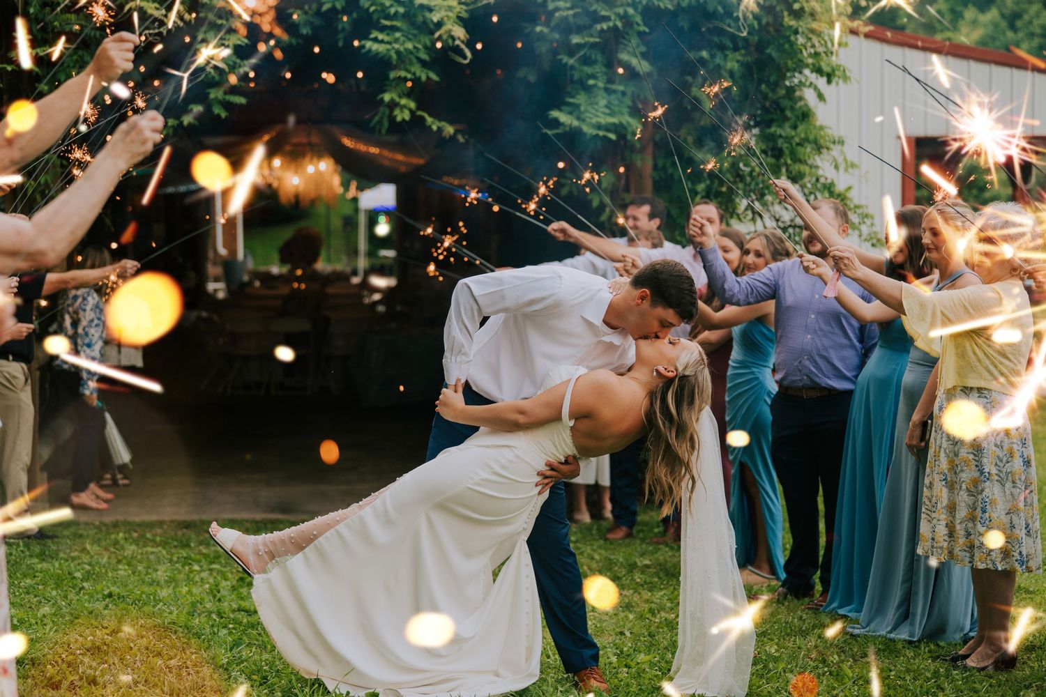 Wedding celebration at dusk with sparklers creating magical light trails in the background.
