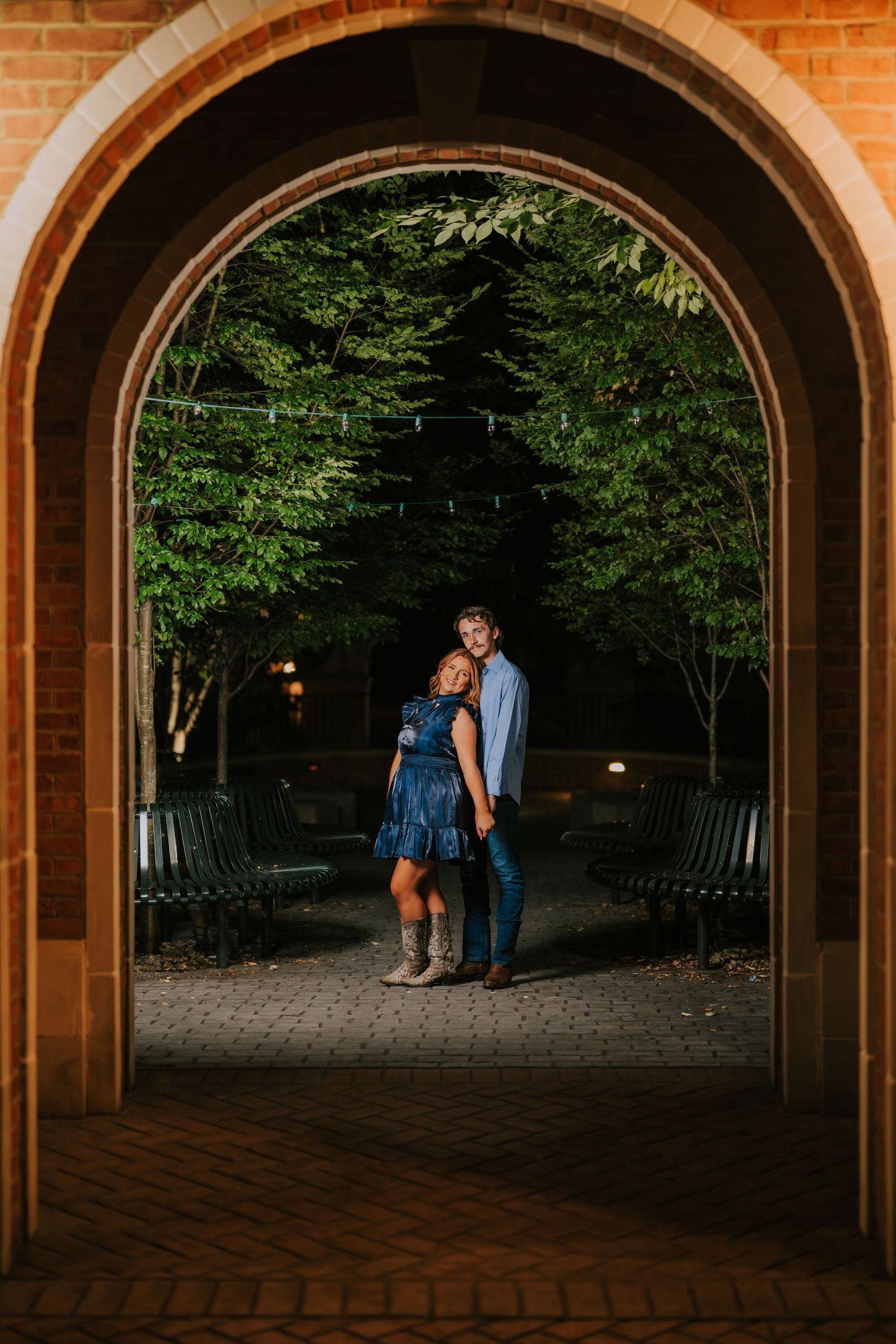 Romantic evening photoshoot under brick archways with dramatic lighting.