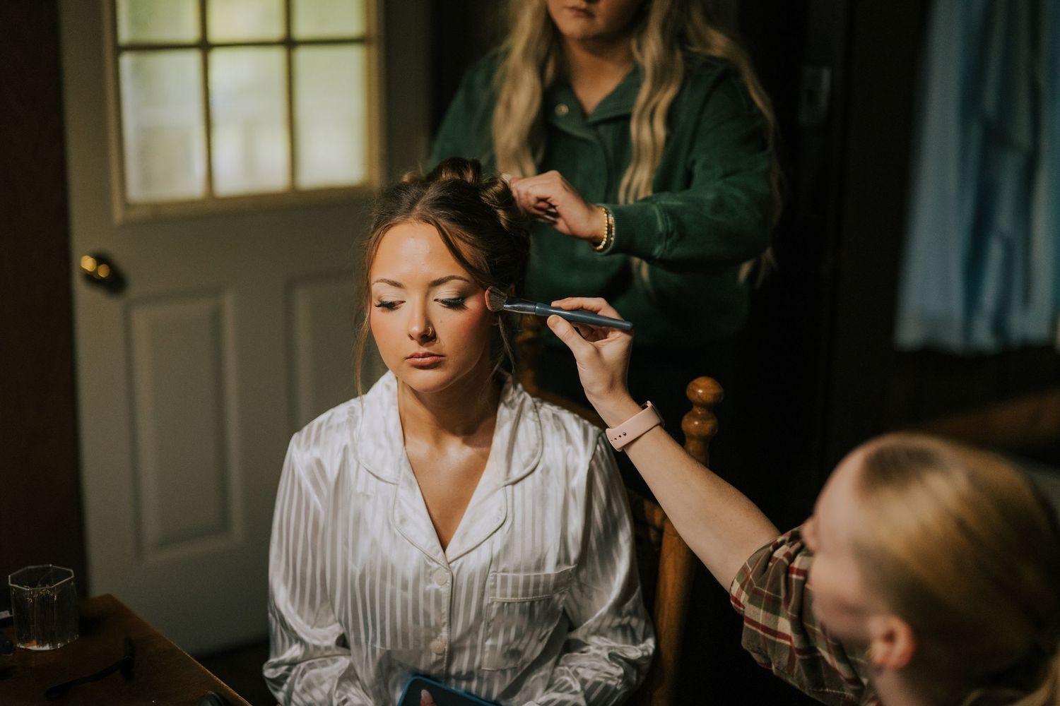 A wedding preparation scene with floral arrangements and people getting ready in a bright room.