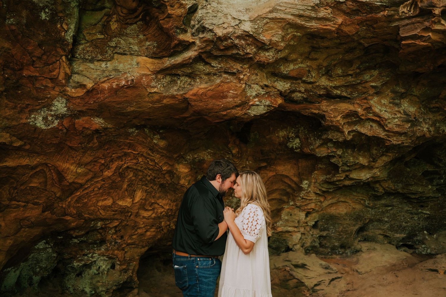 Intimate moment captured under dramatic rock formations and natural cave lighting.