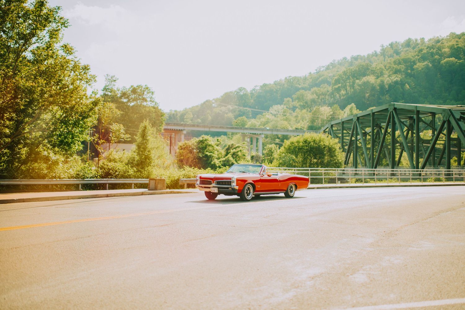 Panoramic view of a winding mountain road with vintage red car in the distance.