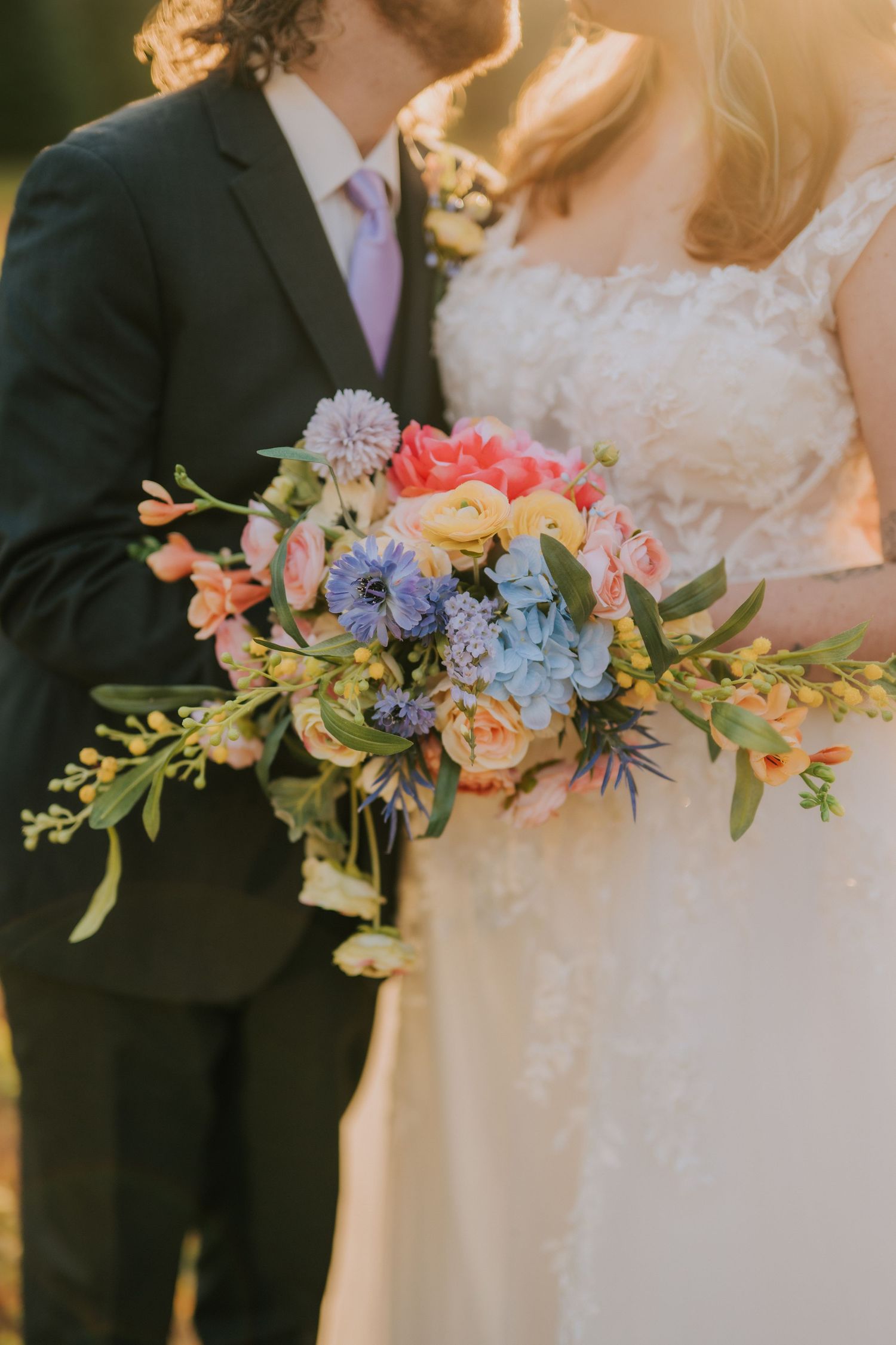 Wedding bouquets featuring pink, blue and coral flowers with greenery.