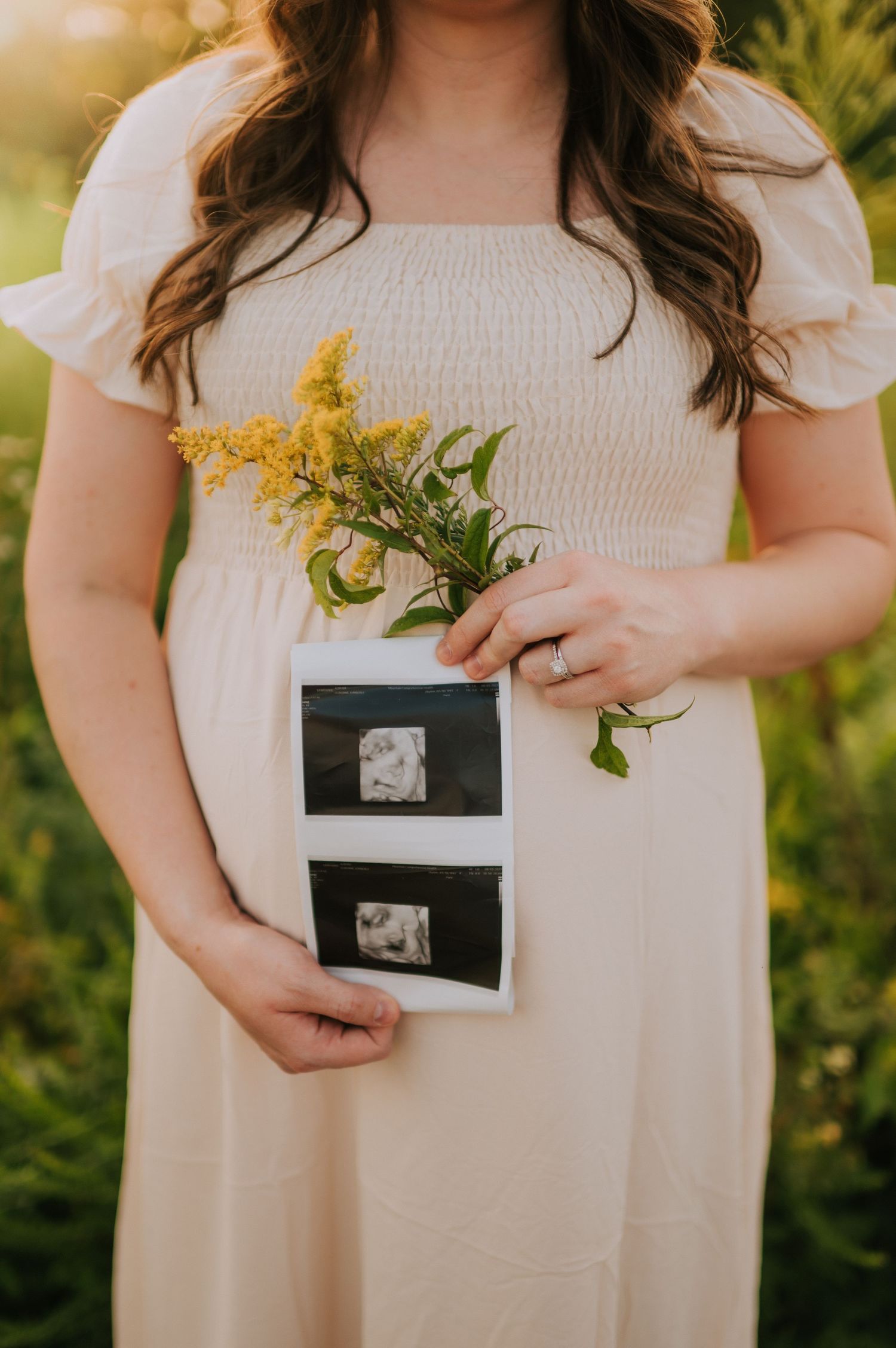 Maternity photo series with white dress and sonogram photos against natural backdrop.