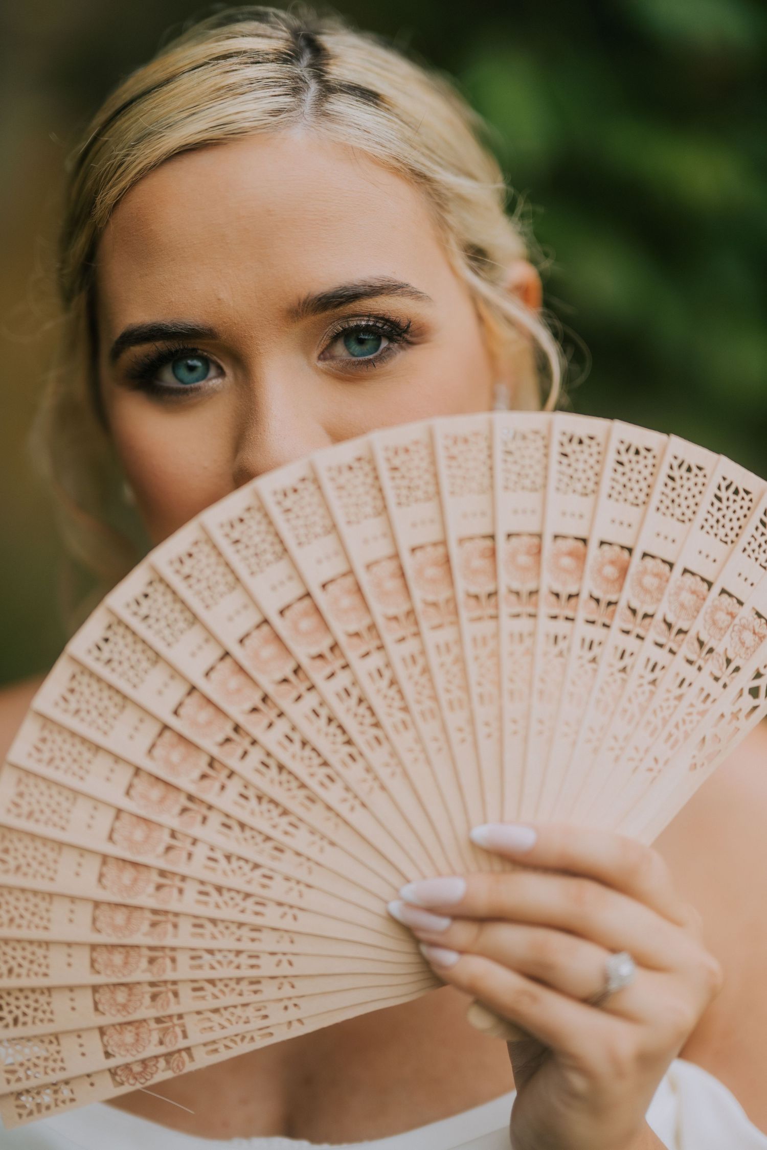 Elegant bridal portrait with a decorative folding fan creating a romantic mood.