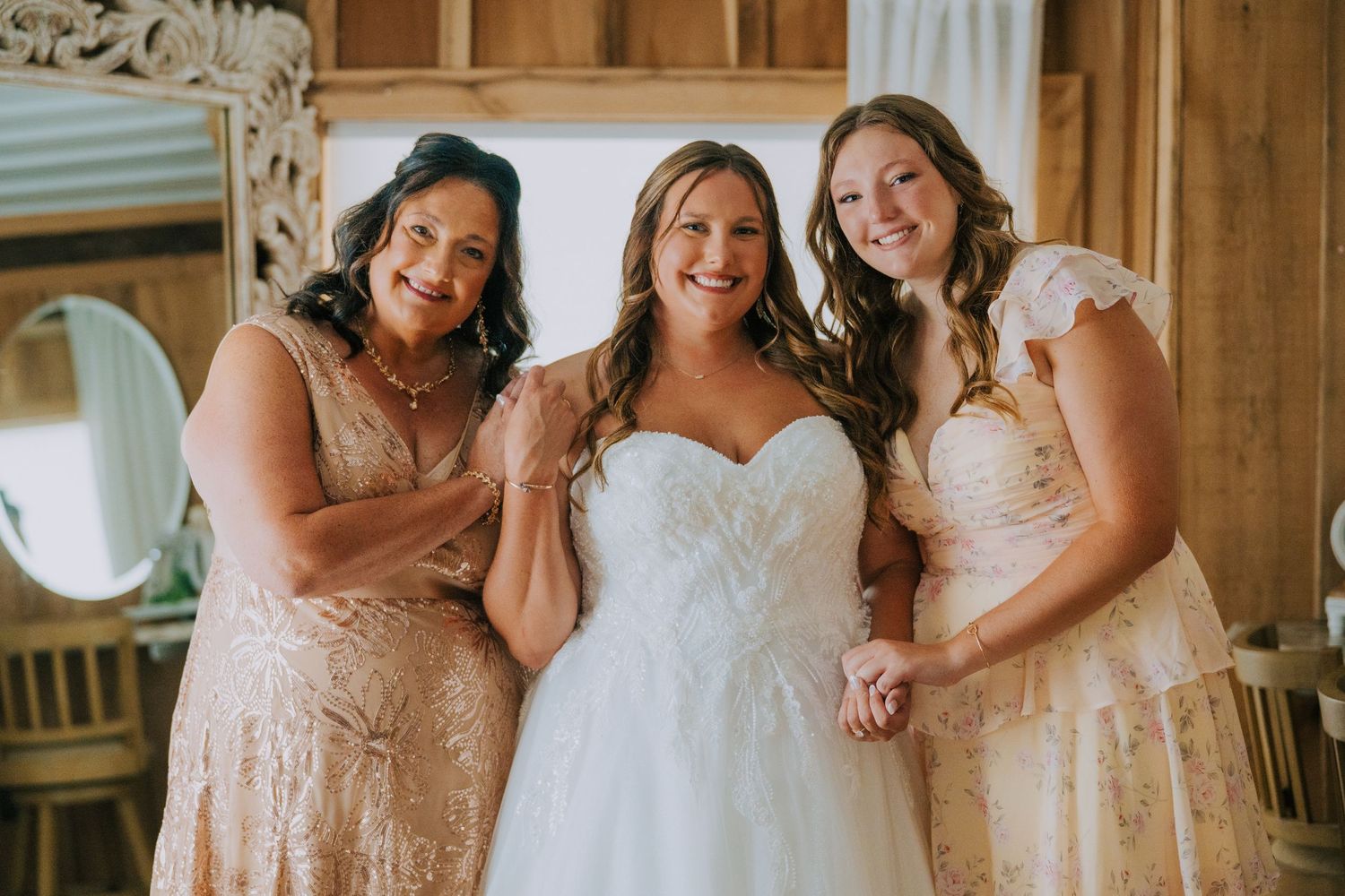 Bridesmaids in blush dresses pose together in a rustic wooden venue.