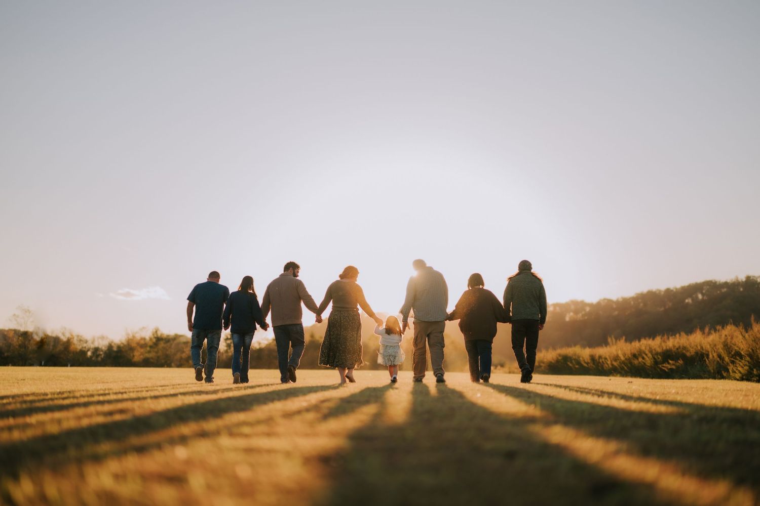 Silhouettes of people walking together against a sunset sky on a hilltop.