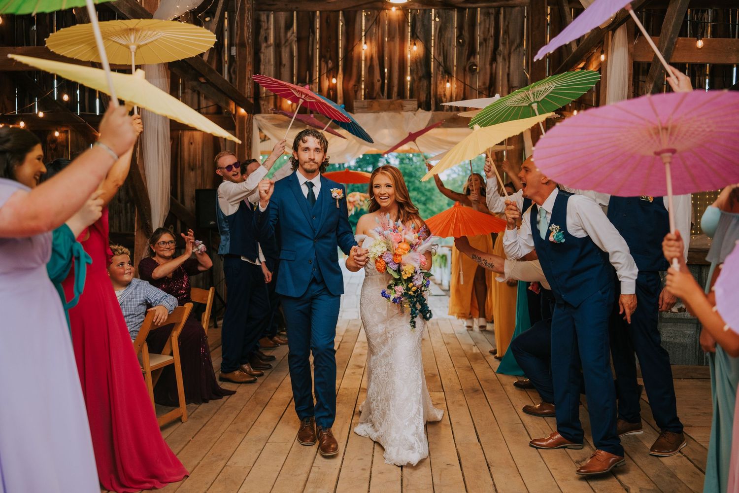 Rustic barn wedding reception with colorful paper lanterns hanging from ceiling.