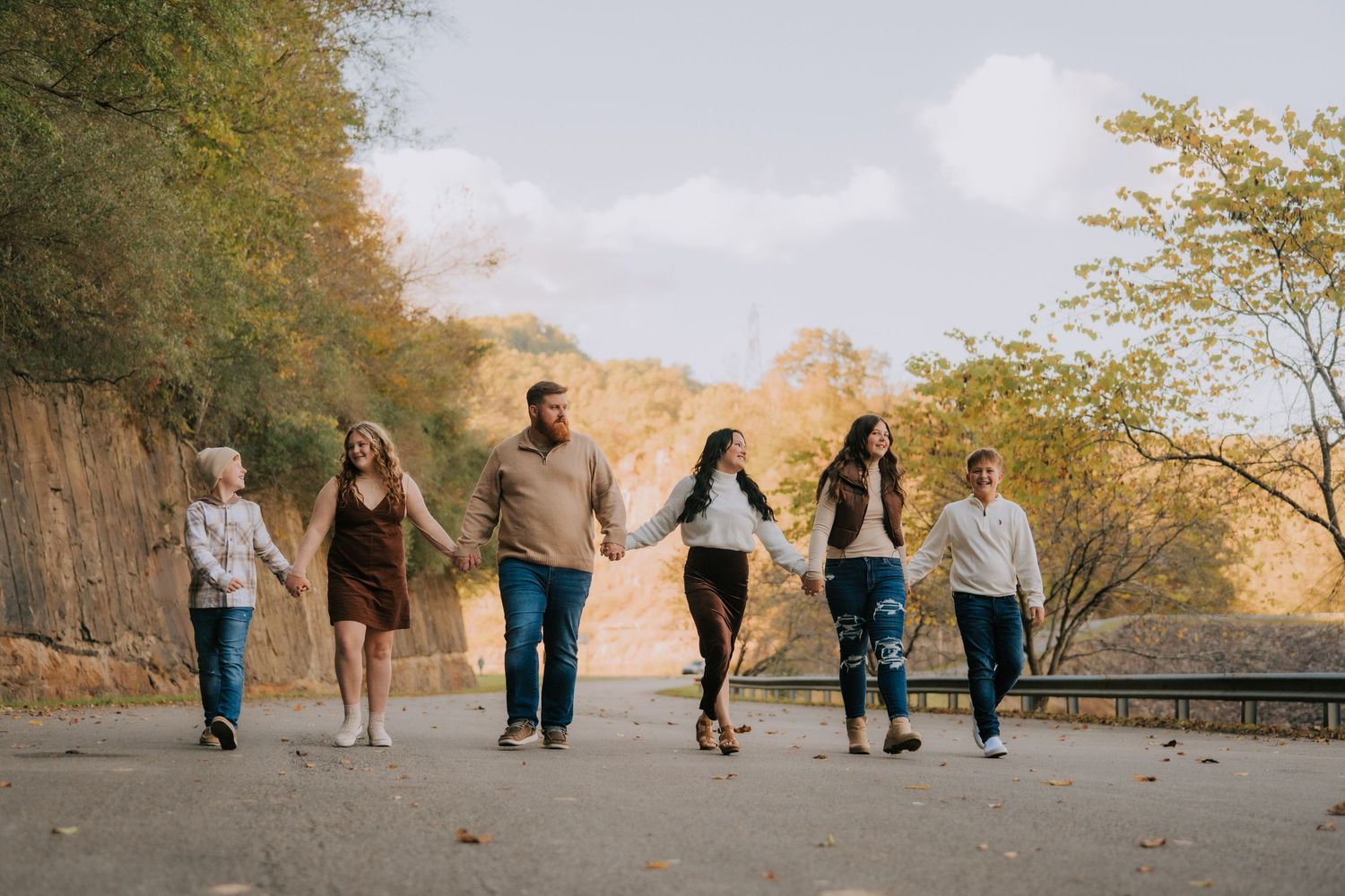 Family walking together along autumn path holding hands.