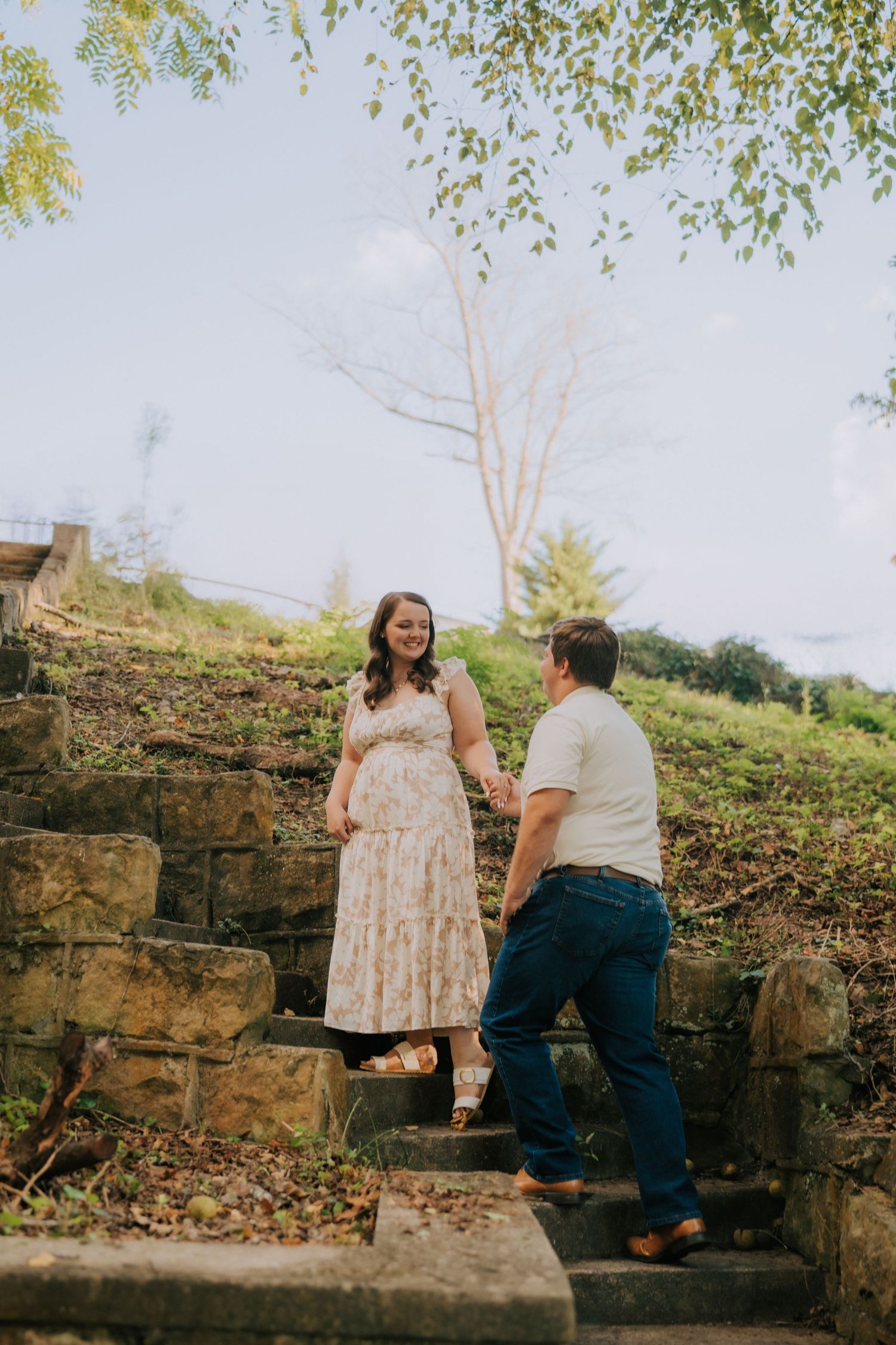 A couple sharing a tender moment while sitting on stone steps outdoors.