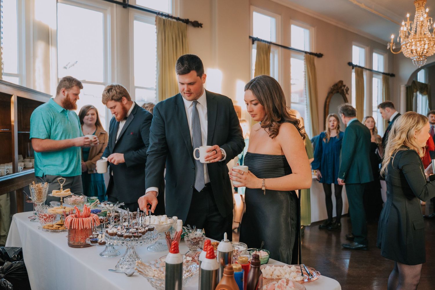 Attendees gather around a drink station at an elegant indoor event while holding their beverages.