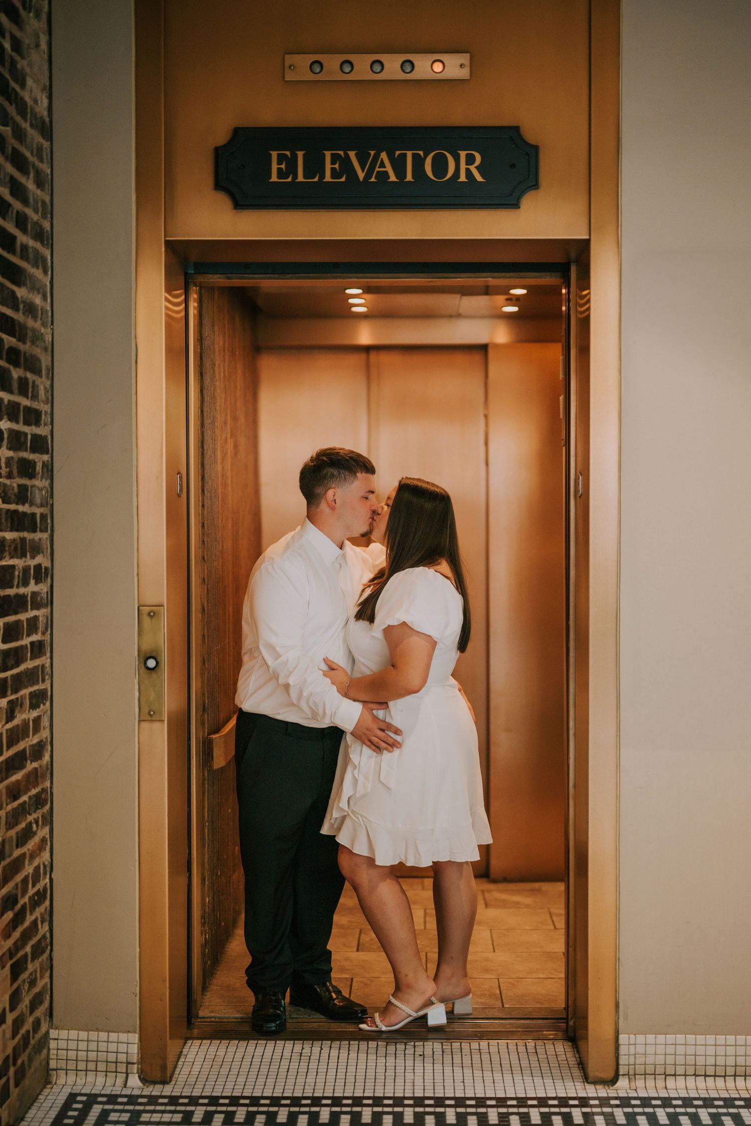 A romantic elevator photoshoot featuring a couple in formal attire sharing intimate moments.