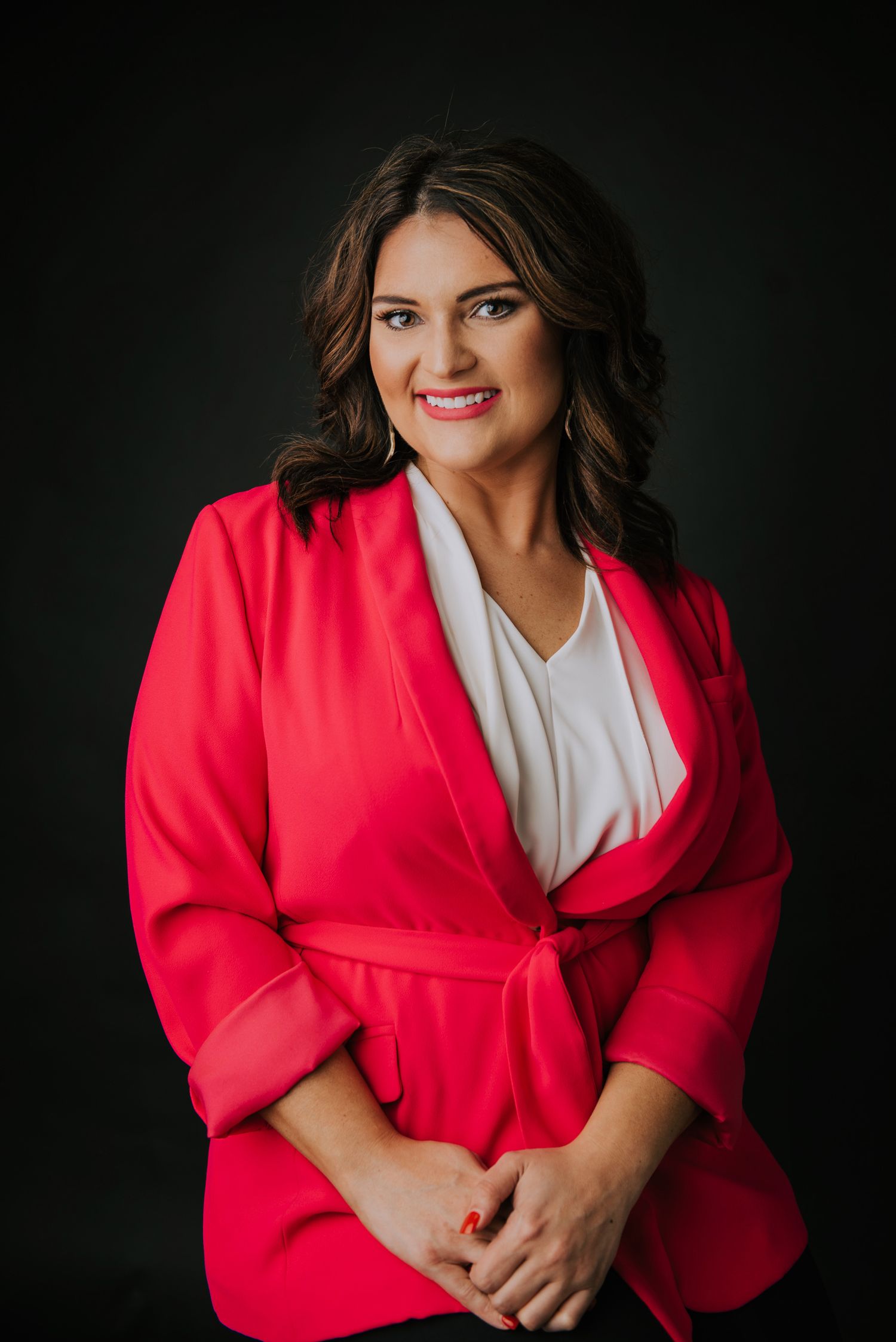 Professional headshots featuring a bright red blazer and white top against dark backdrop.