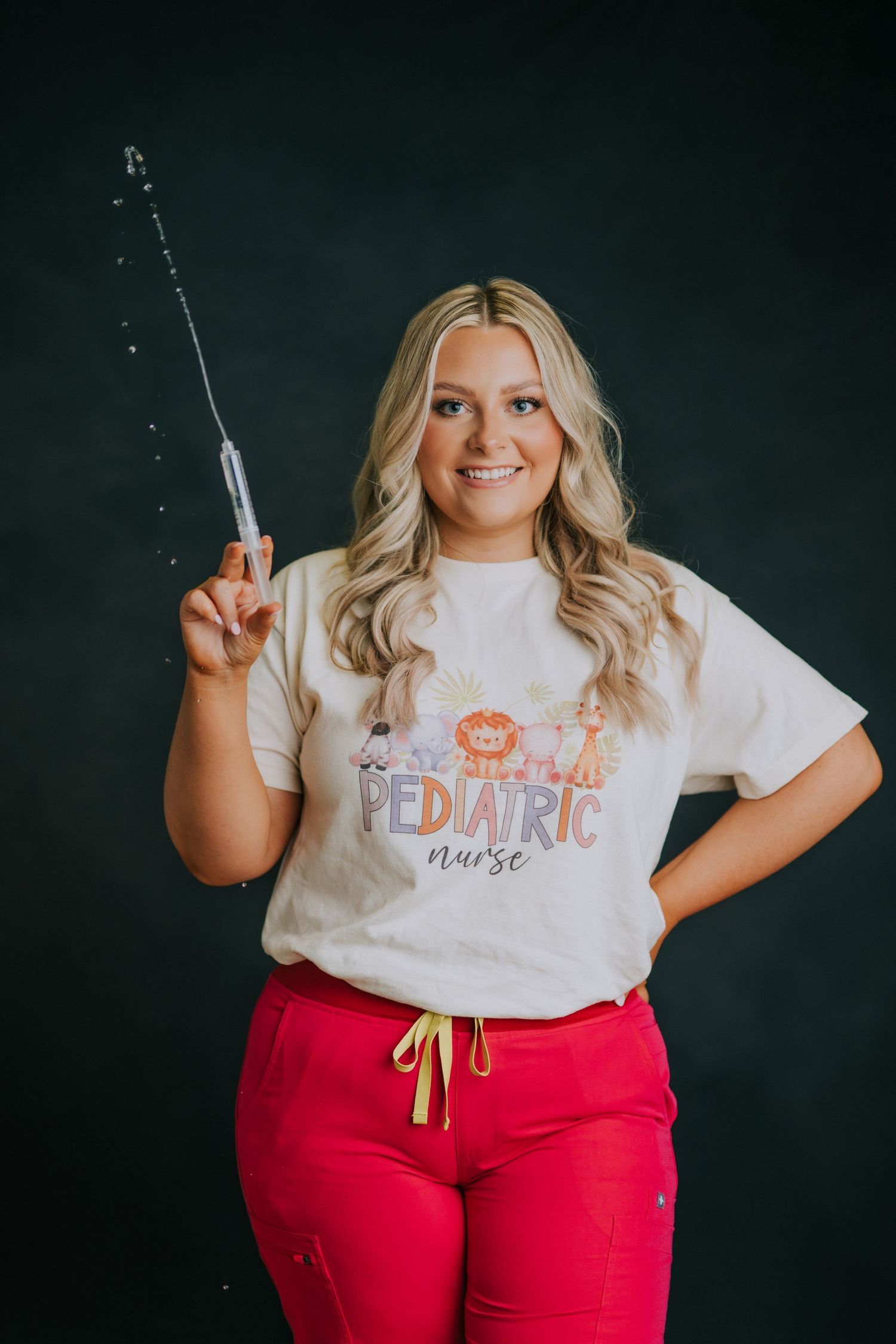 Studio portraits with a white t-shirt and red pants against a dark background.