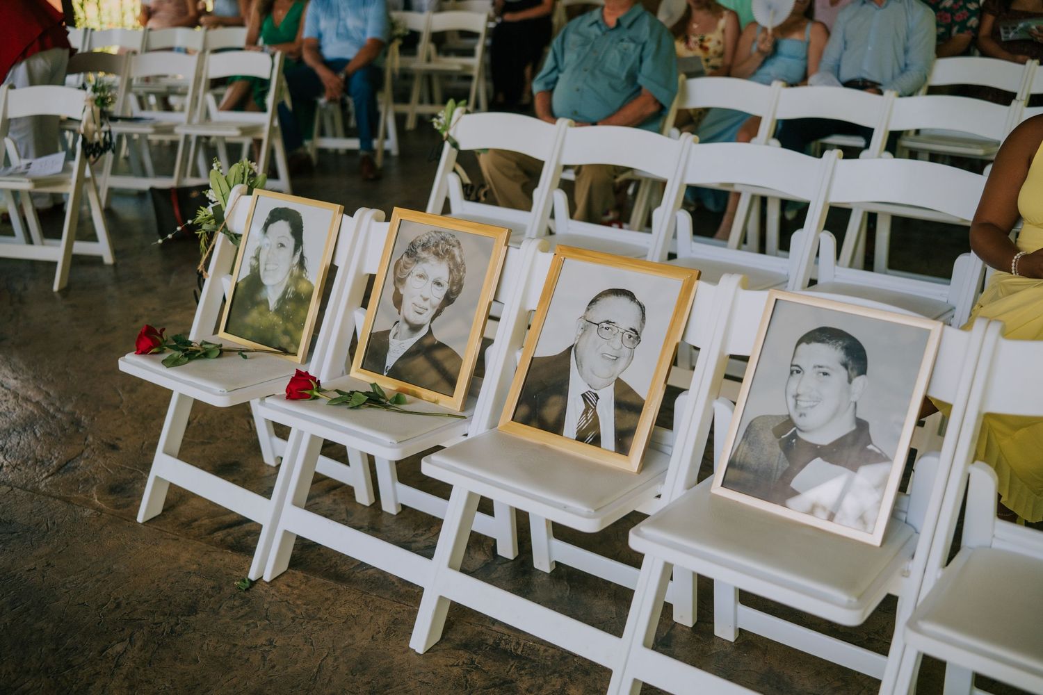 Memorial photos of loved ones displayed on white folding chairs at a wedding ceremony.