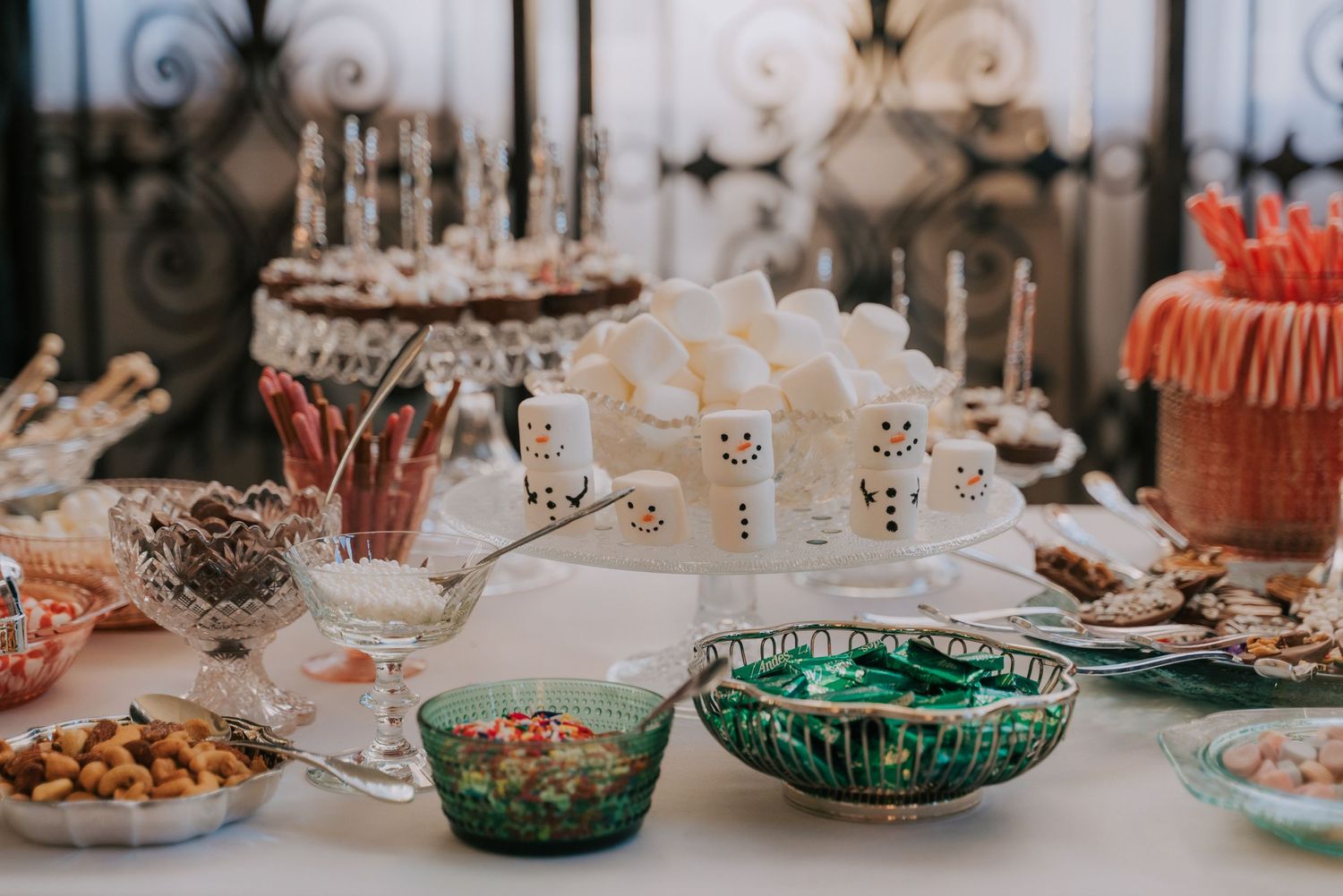 An elegant party table setting with vintage glassware, snack bowls, and dessert plates arranged for a special occasion.