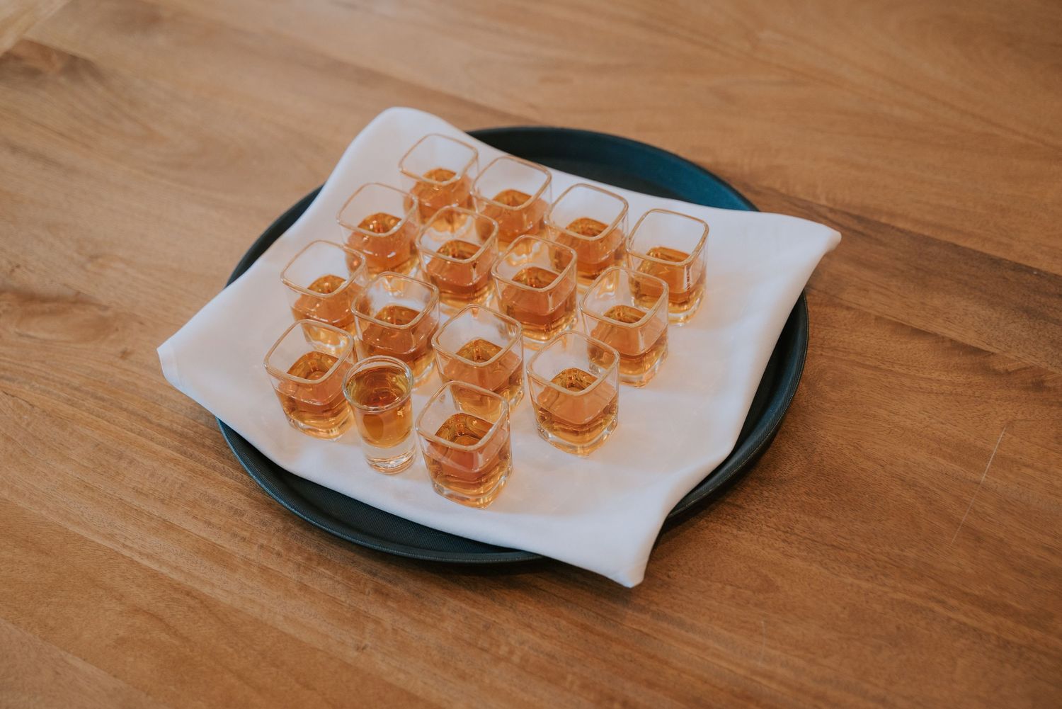 Small appetizer bites arranged in neat rows on a white paper-lined green plate on a wooden table.