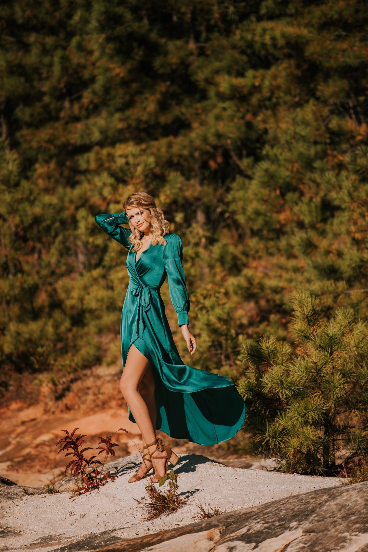Flowing teal dress movement captured against rocky terrain in dramatic outdoor photoshoot.