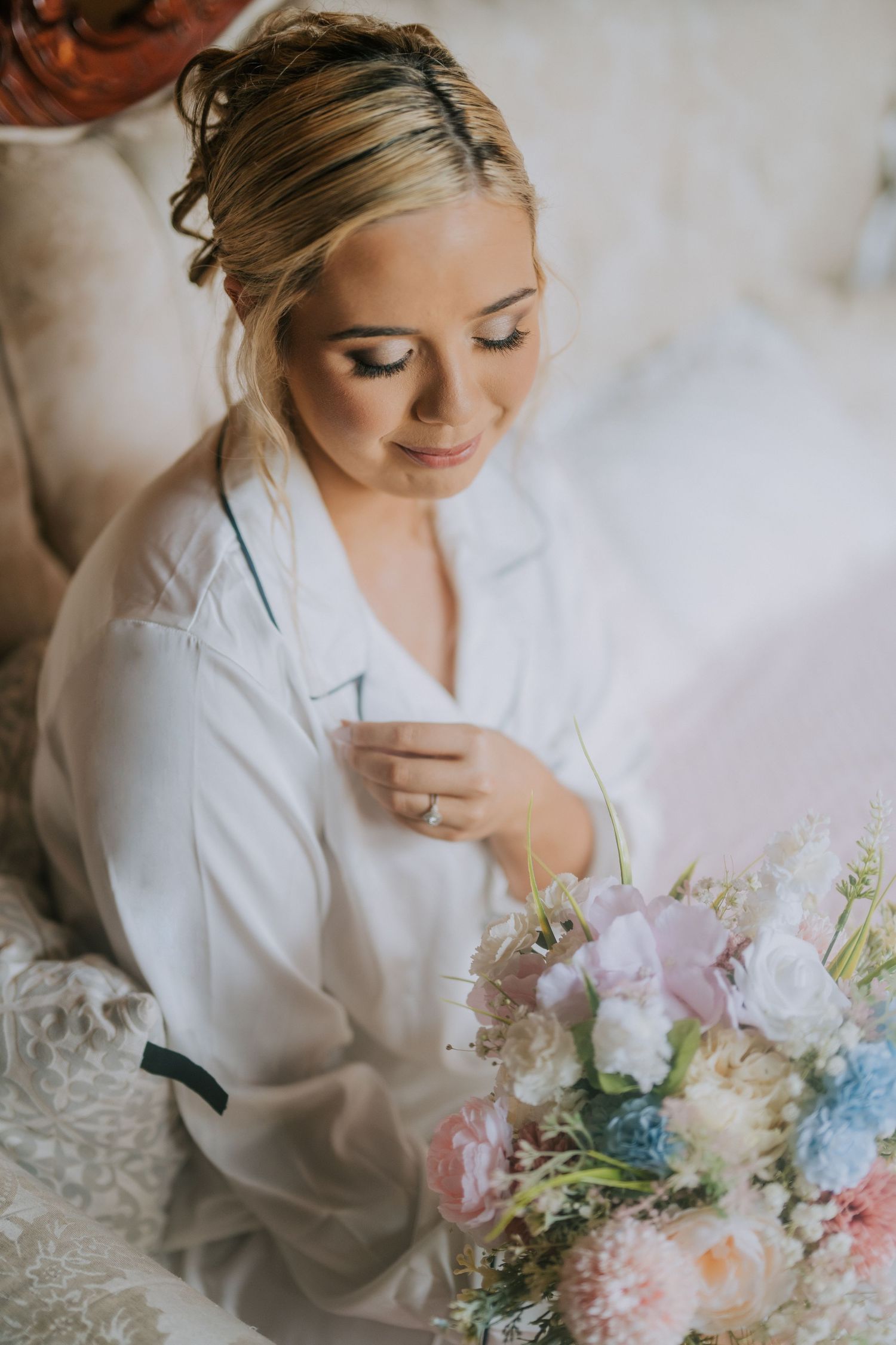 A delicate bridal preparation scene with pastel flowers and a white robe in soft morning light.