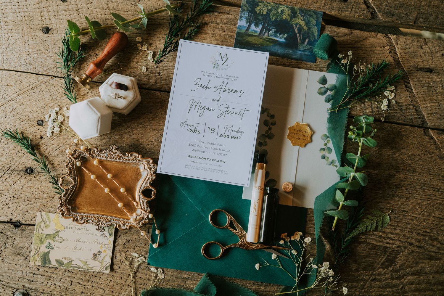 Wedding stationery flatlay with green accents, scissors, and vintage decor on wooden surface.