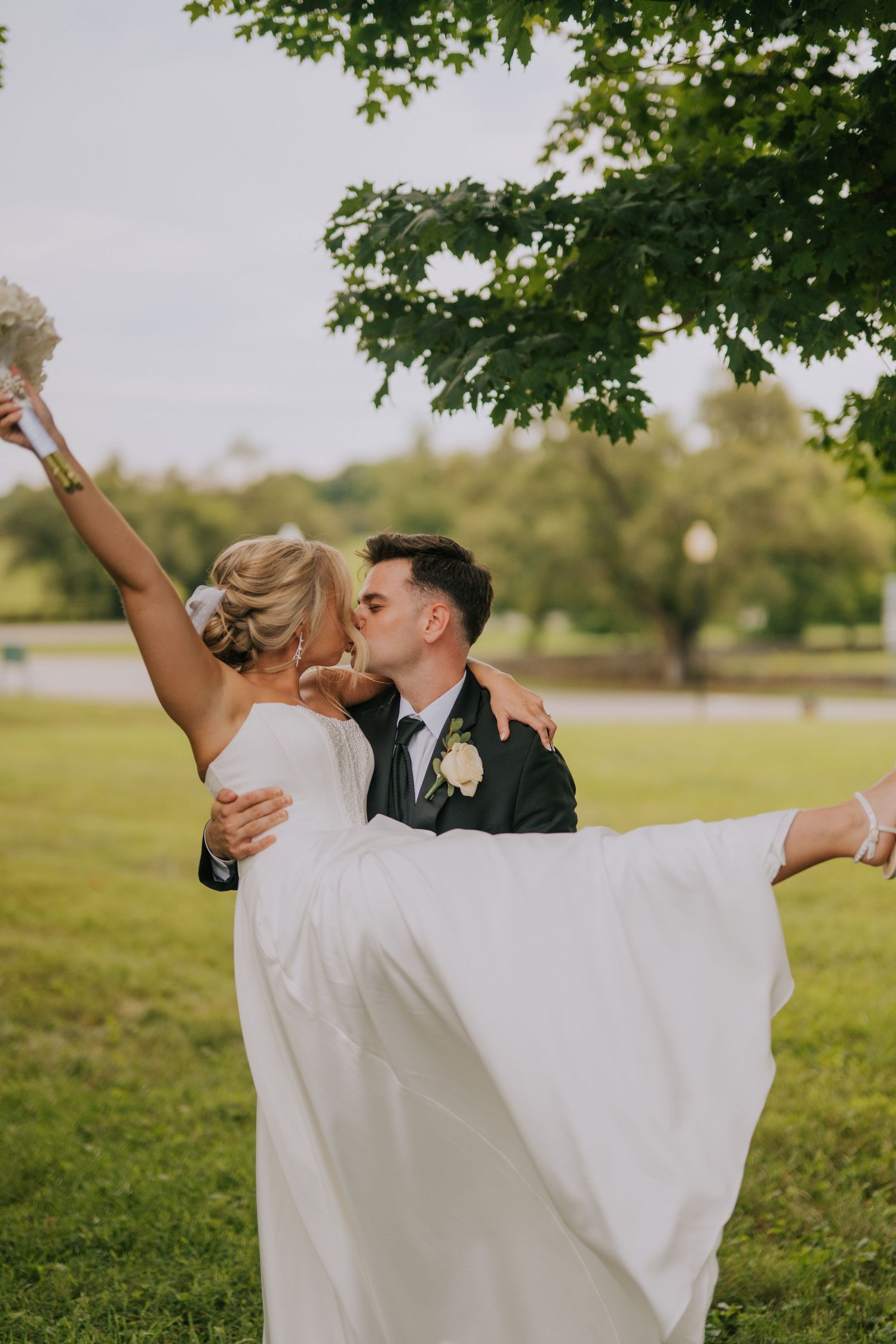 Joyful outdoor wedding portraits with flowing veil in natural setting.