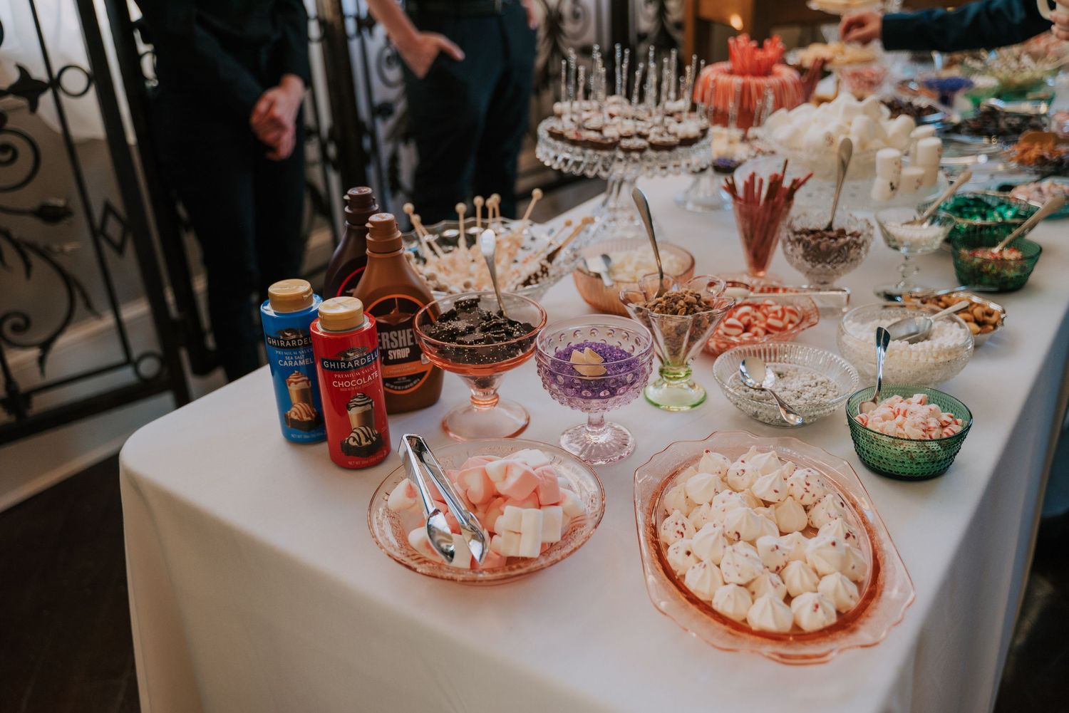 Party snack table with candy bowls, popcorn, drinks and festive appetizers set up on white tablecloth for celebration.