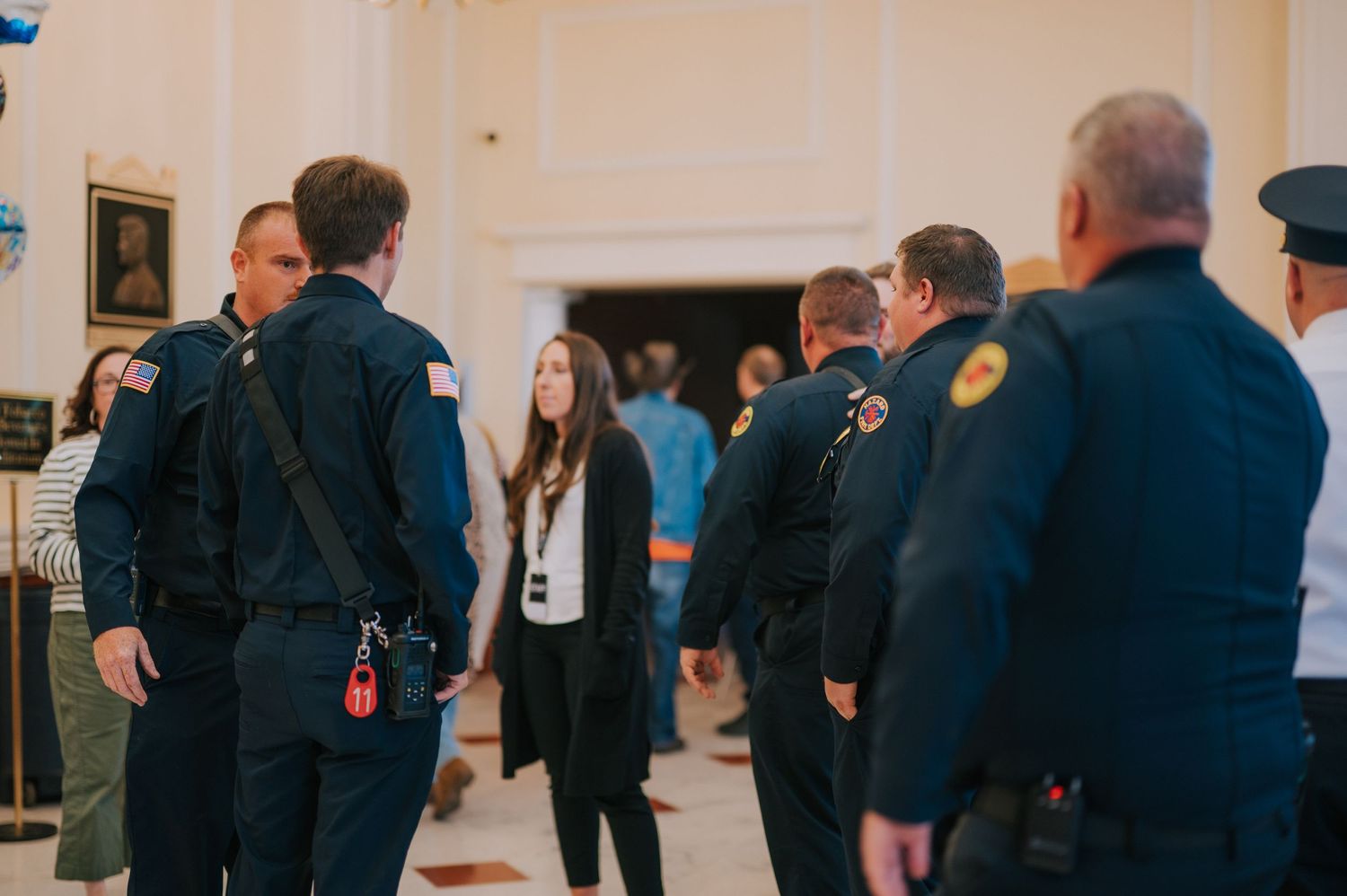People gathered in a formal indoor setting wearing uniforms and professional attire.