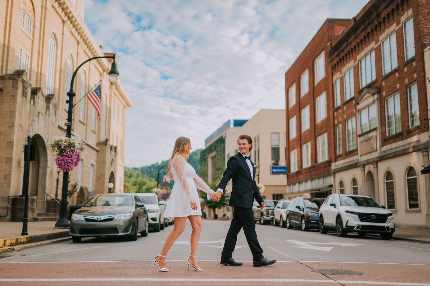 A couple walks down a historic small town street lined with classic architecture.