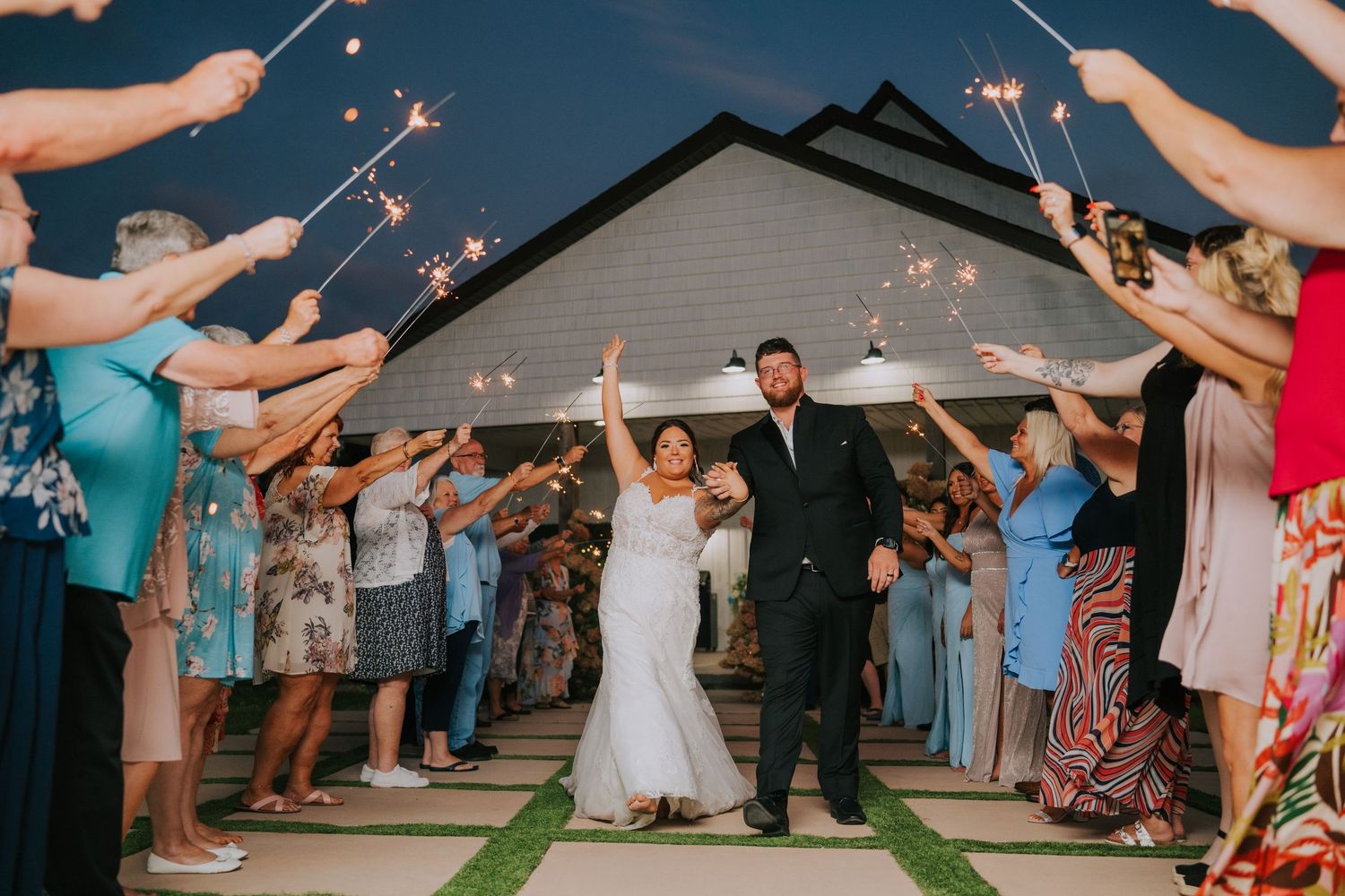 Wedding guests create a sparkler tunnel exit for the newlyweds during evening celebrations.