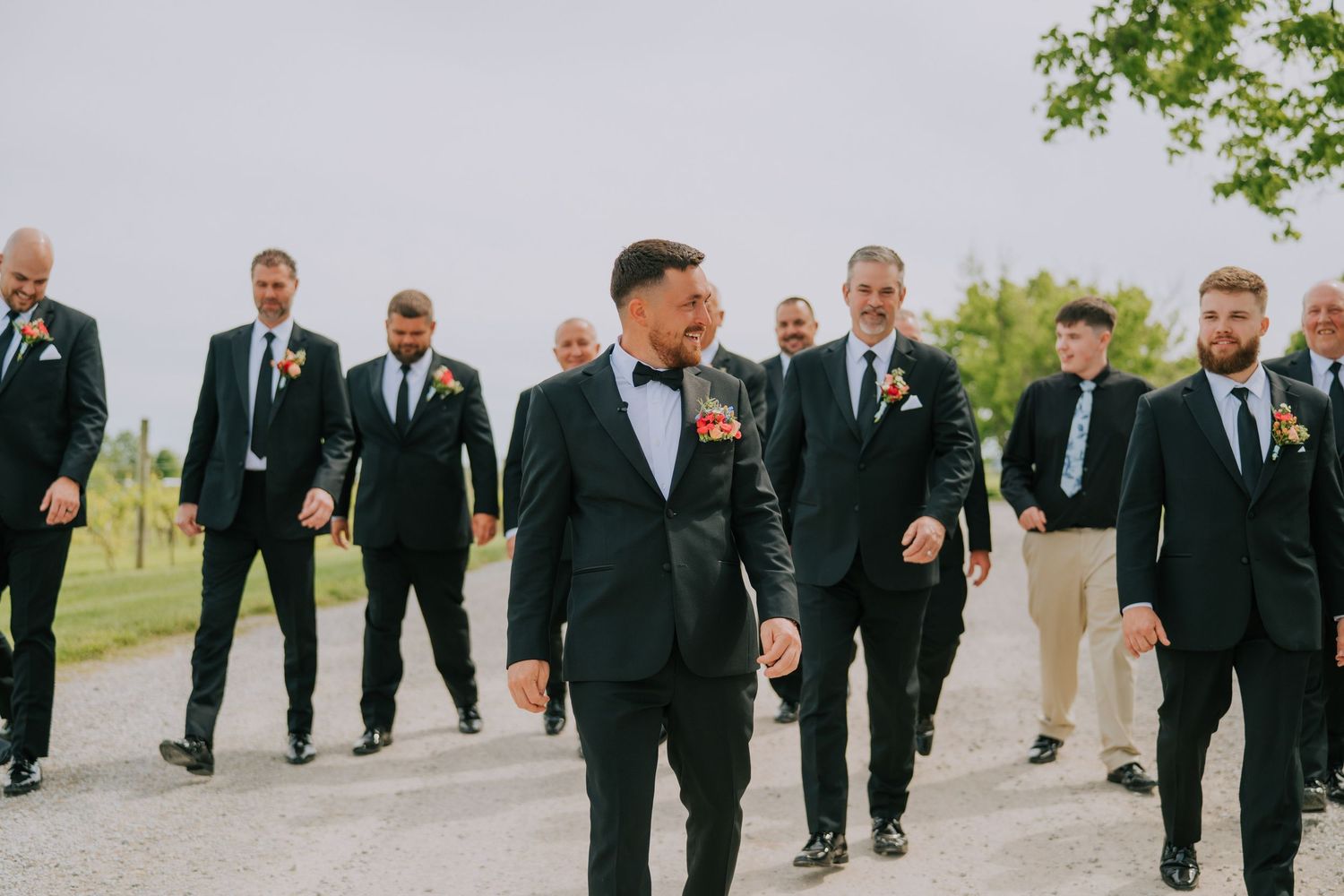 Wedding party of groomsmen walking together on a path wearing formal black suits.