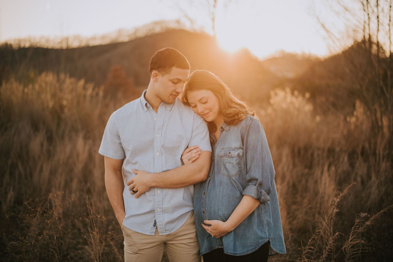 Golden hour family photoshoot in tall grass field at sunset.
