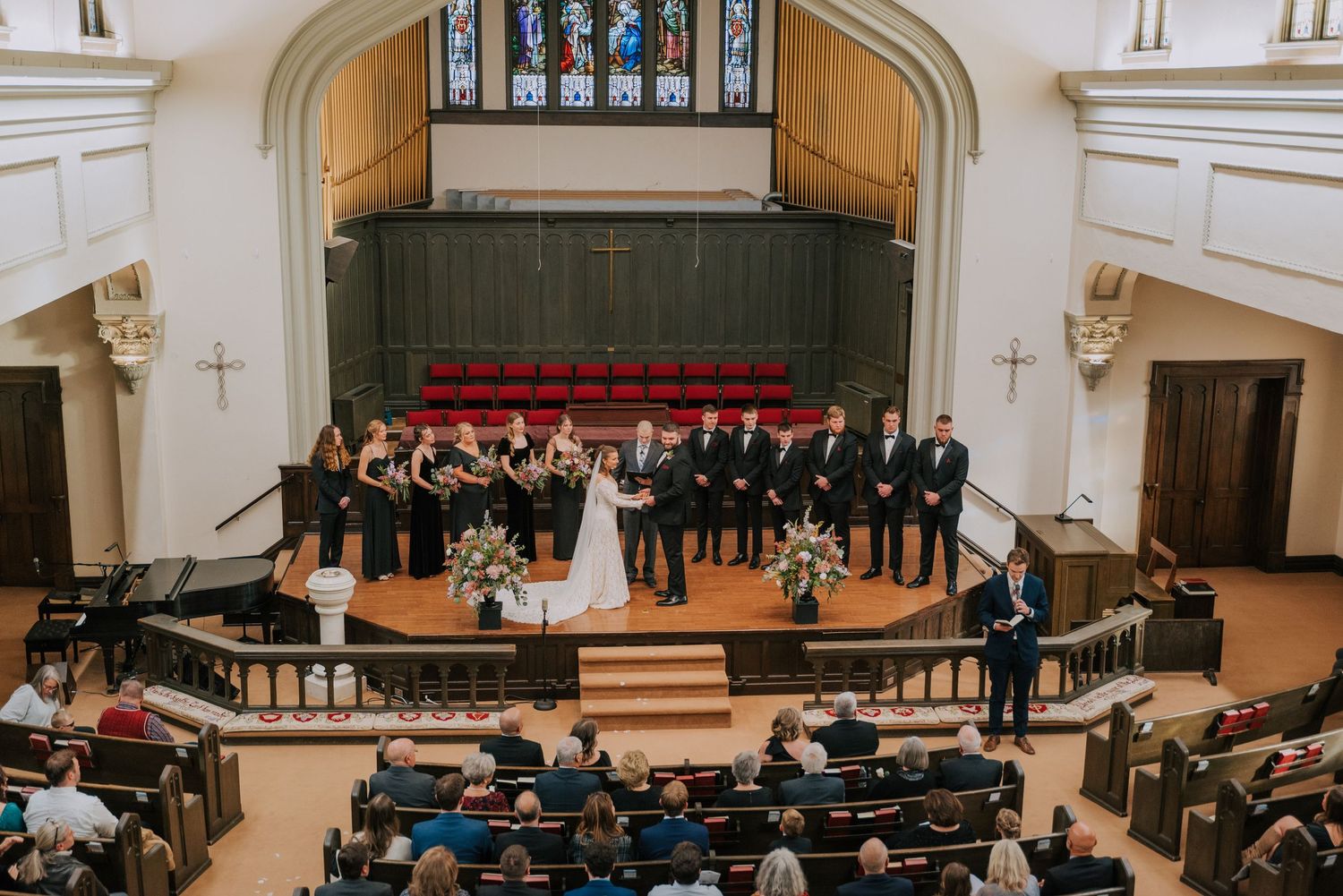 Large choir performs behind a couple during wedding ceremony in a grand church sanctuary.