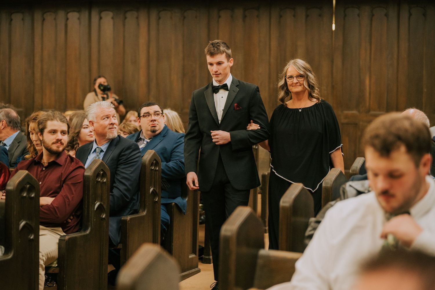 Wedding guests seated in wooden pews during a traditional church ceremony.
