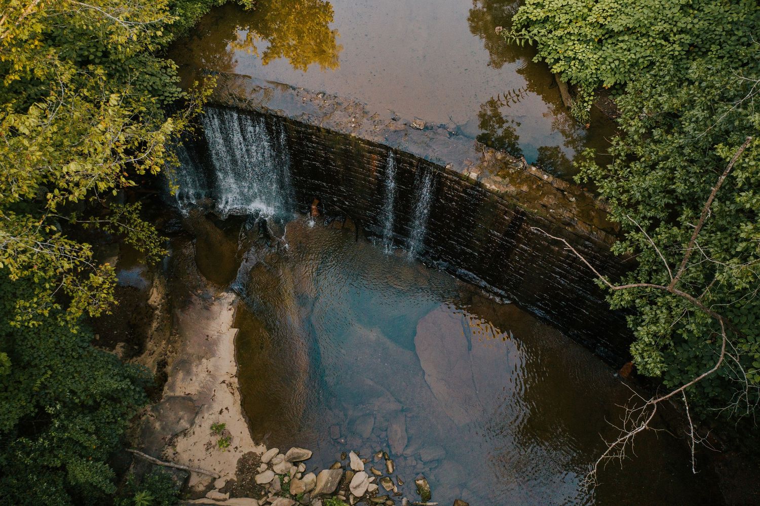 Aerial view of river winding through autumn trees with golden foliage.