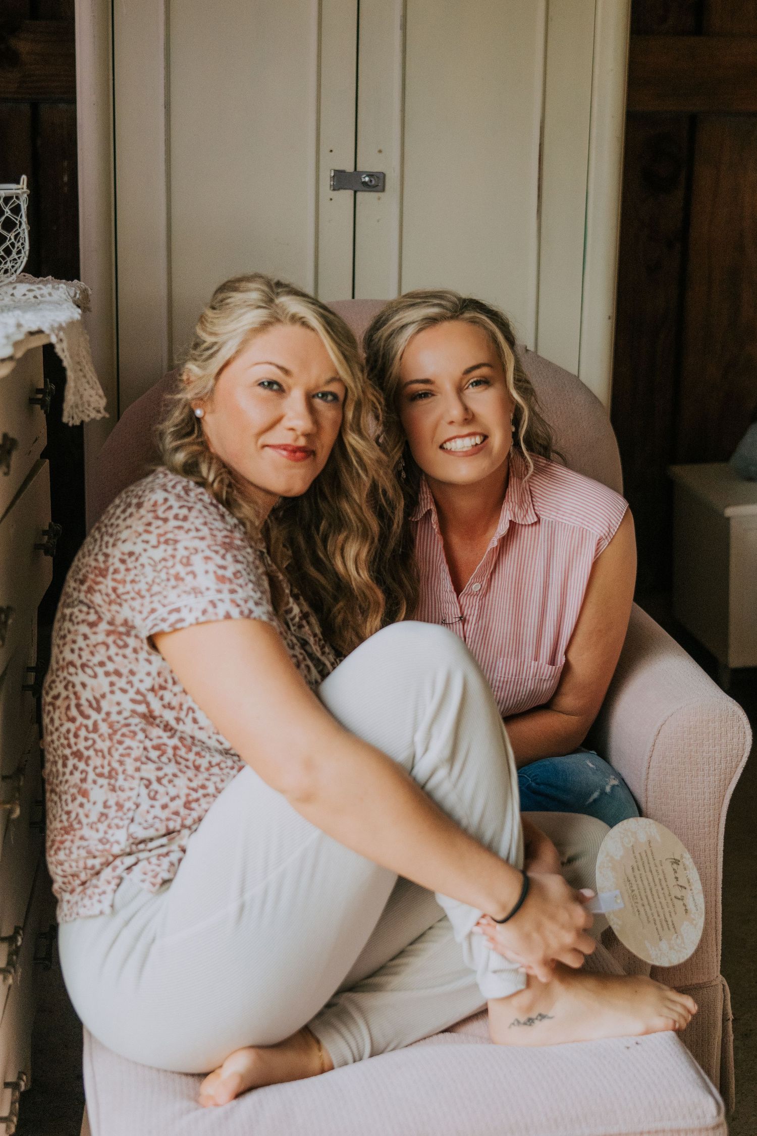 Two friends relaxing and laughing together on a comfortable chair.