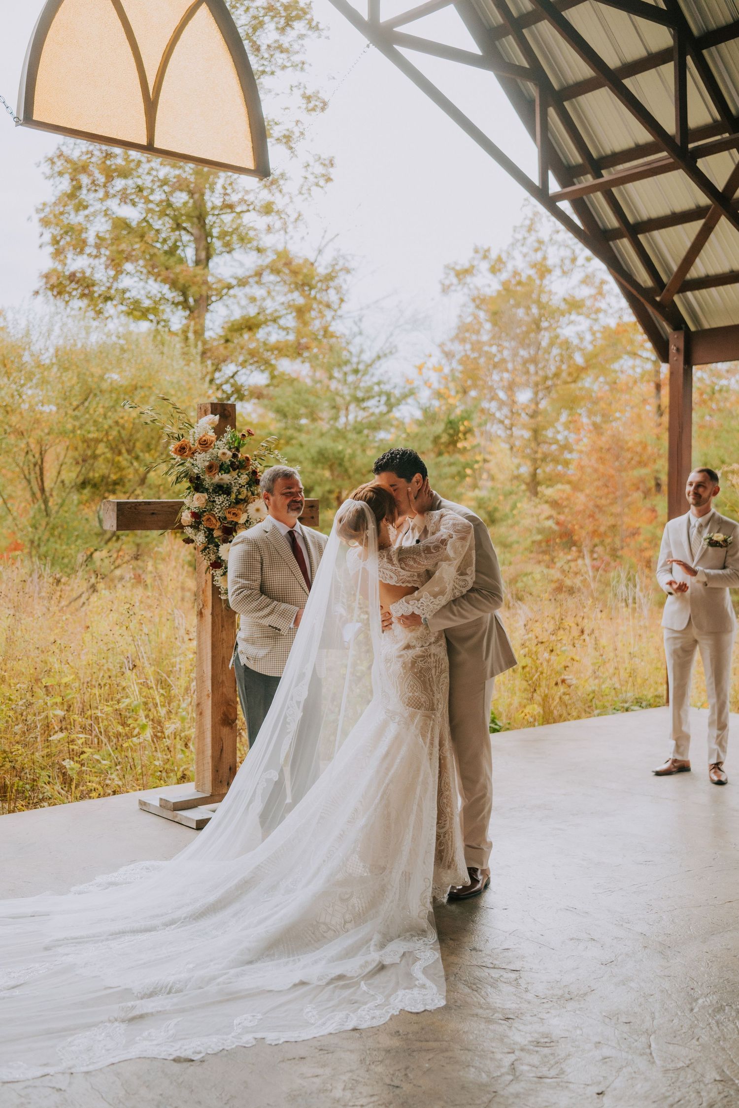 Couple shares romantic moments under a rustic pavilion with flowing white wedding dress.