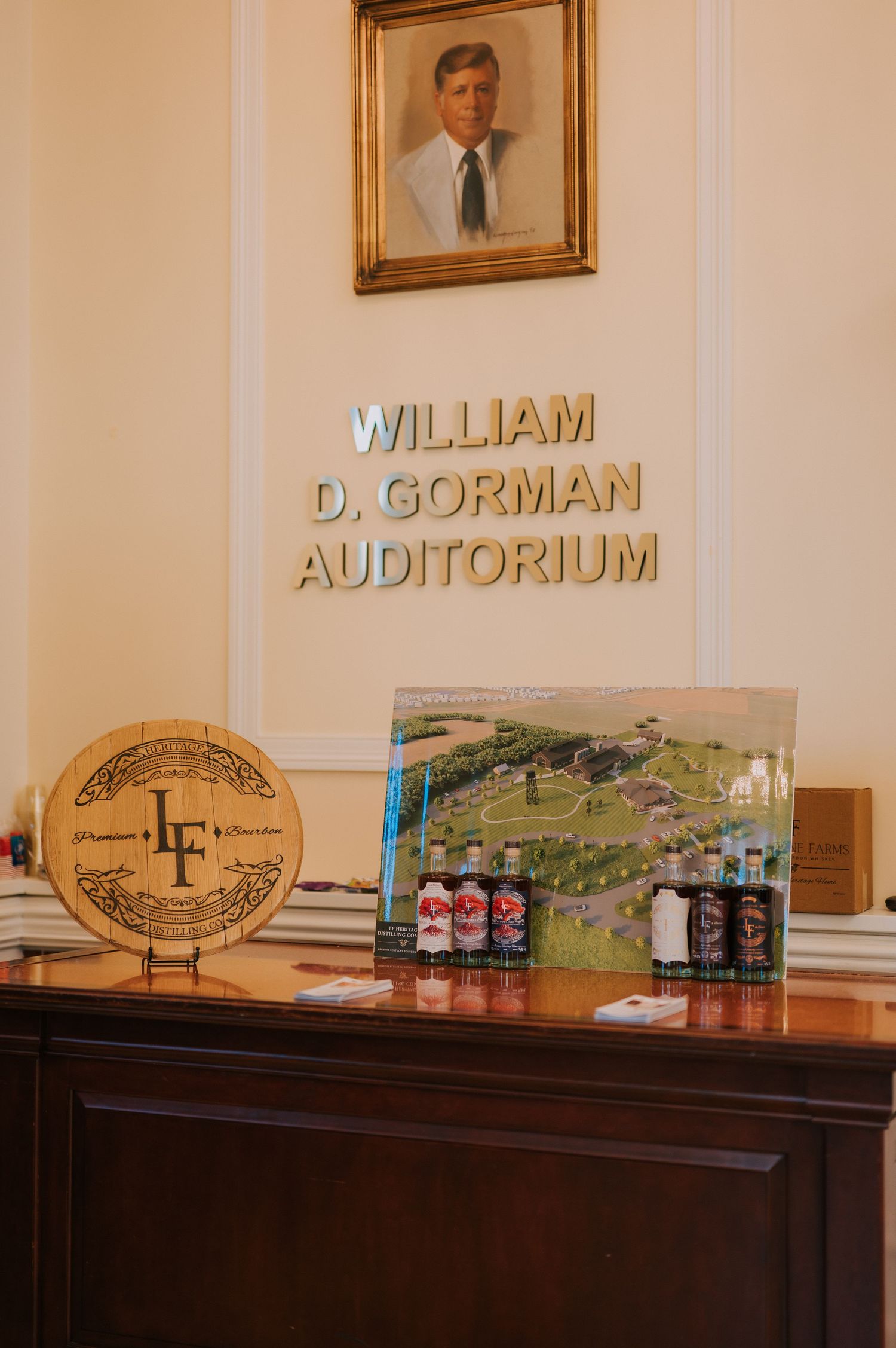 Display at the William D. Gorman Auditorium features decorative seal, portrait and drinks on a wooden surface.