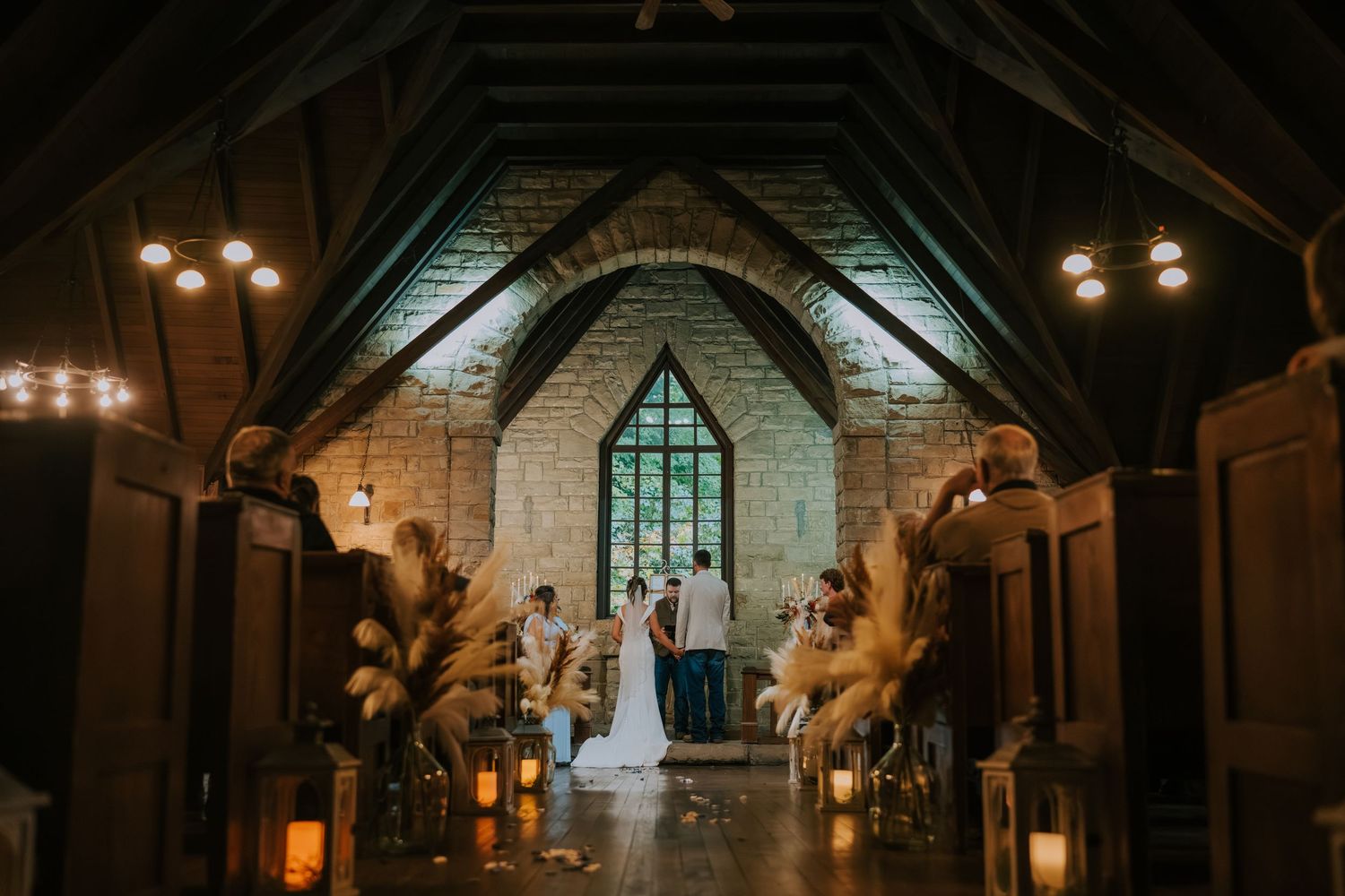 Dimly lit stone church interior with warm lighting and arched windows creating a romantic, atmospheric ambiance.