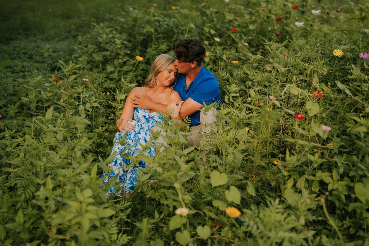 A romantic couple embraces in a lush garden setting with vibrant greenery and flowers.