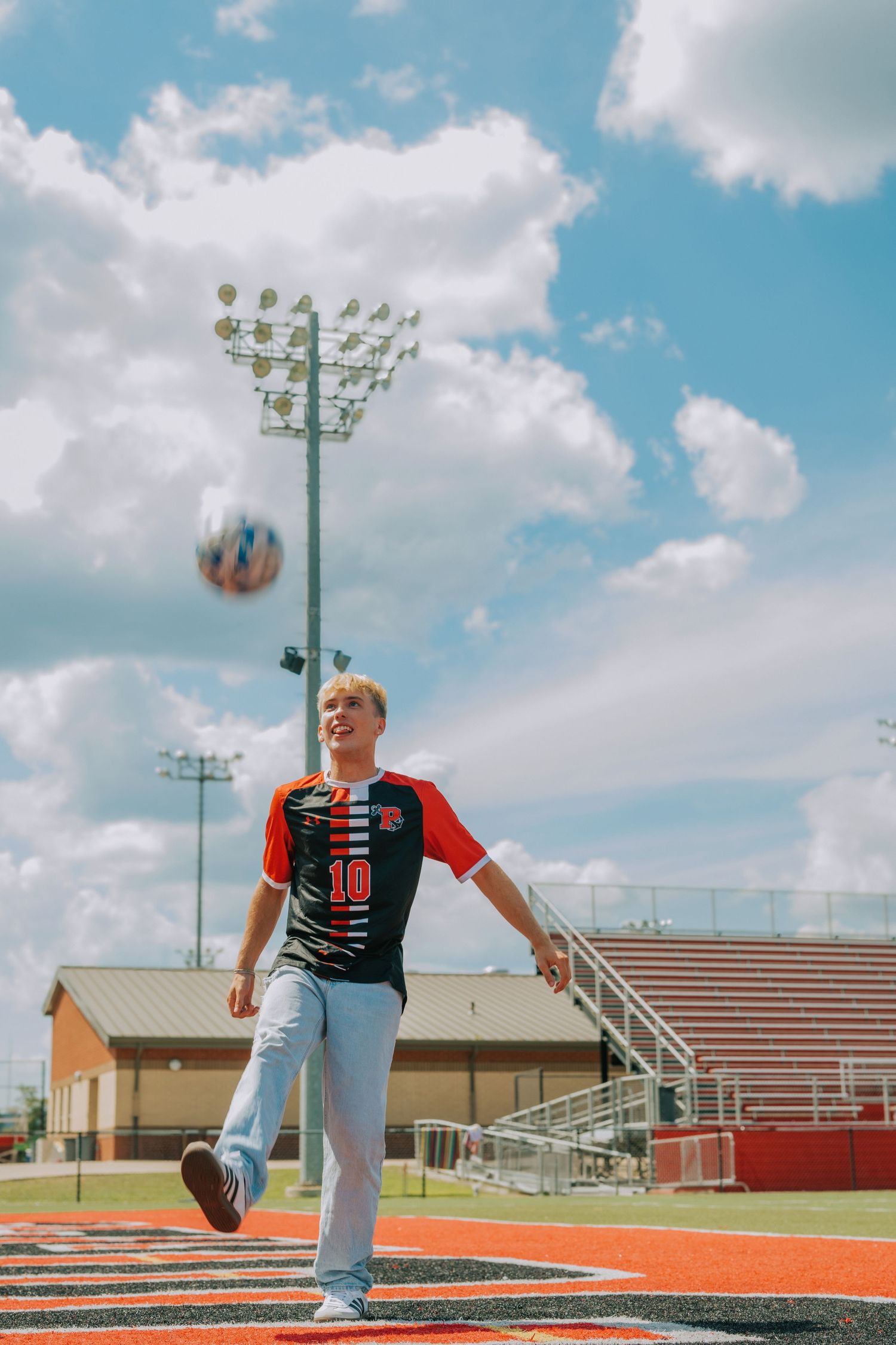 A series of four photos showing a person in casual attire posing on a high school track and field facility.