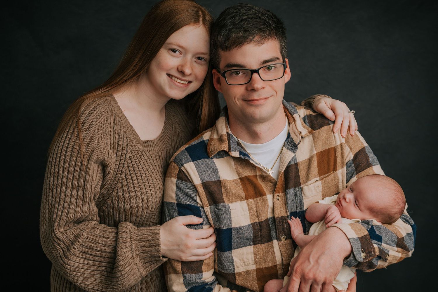 A couple in cozy sweaters share an intimate moment against a dark background.