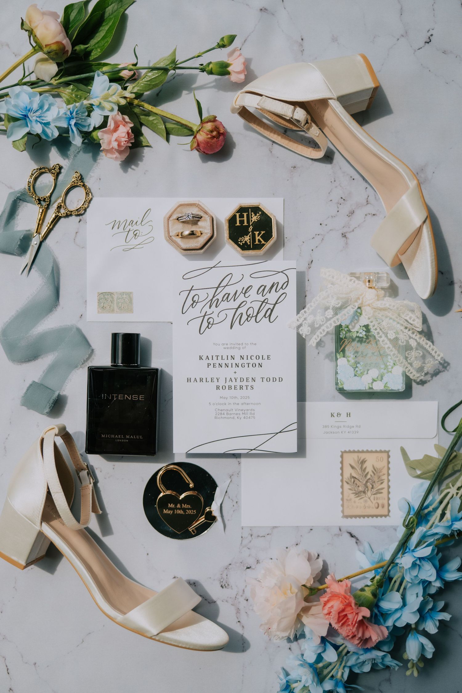 Wedding details flatlay with invitations, shoes, flowers and perfume on marble background.