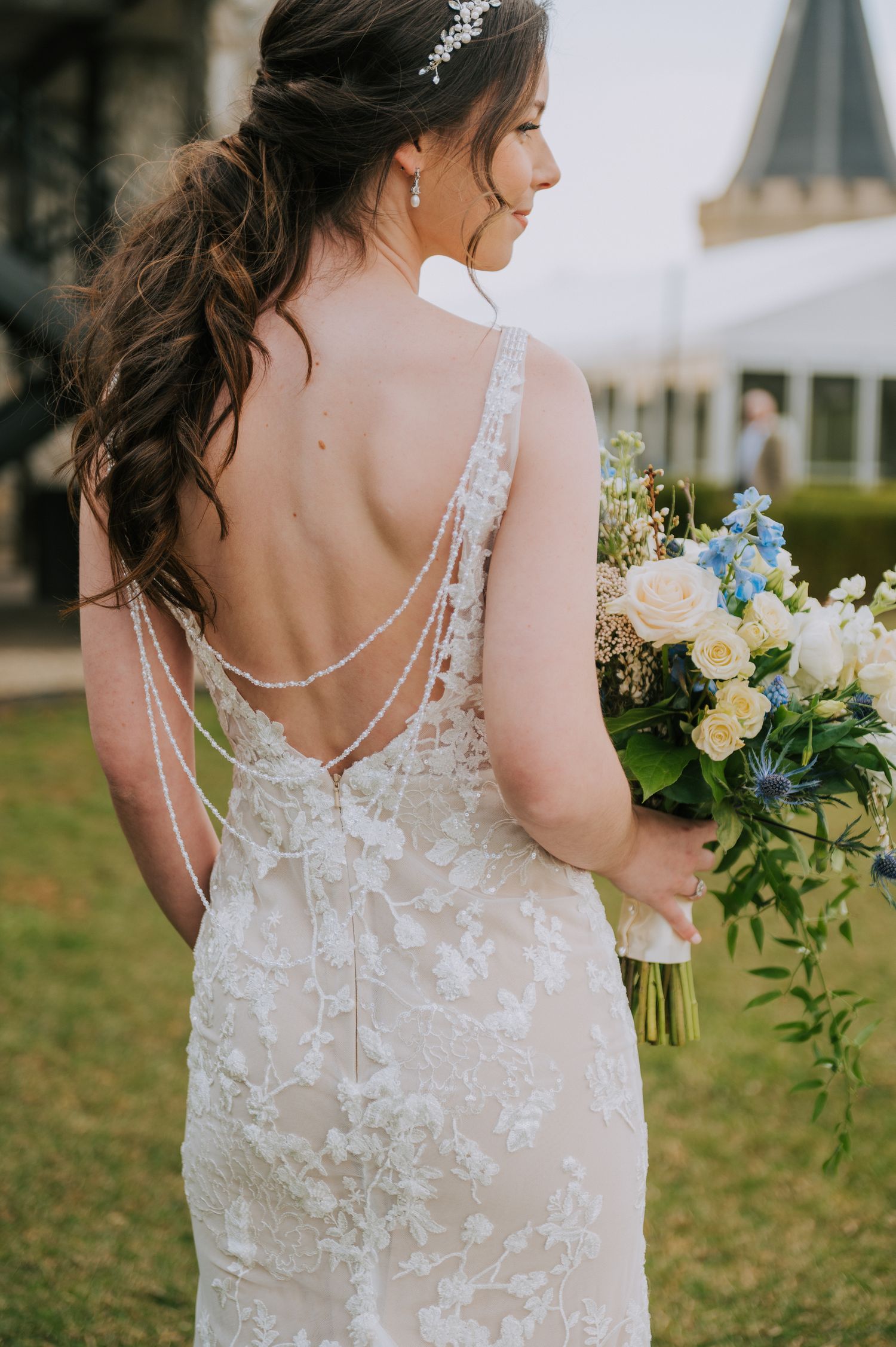 Back view of lace wedding dress with delicate buttons and floral bouquet.
