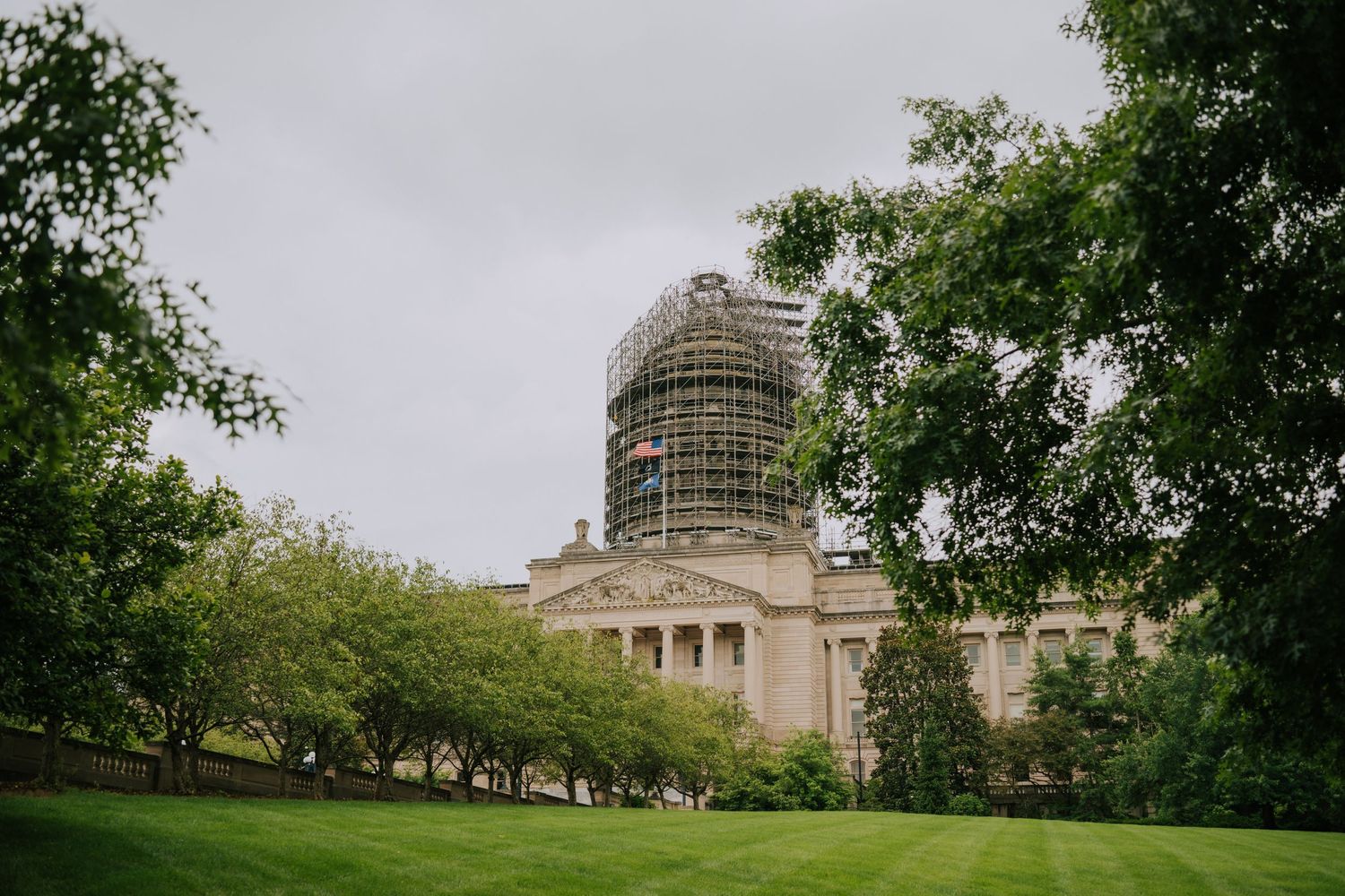 Historic stone building with scaffolding around its domed tower under cloudy skies.
