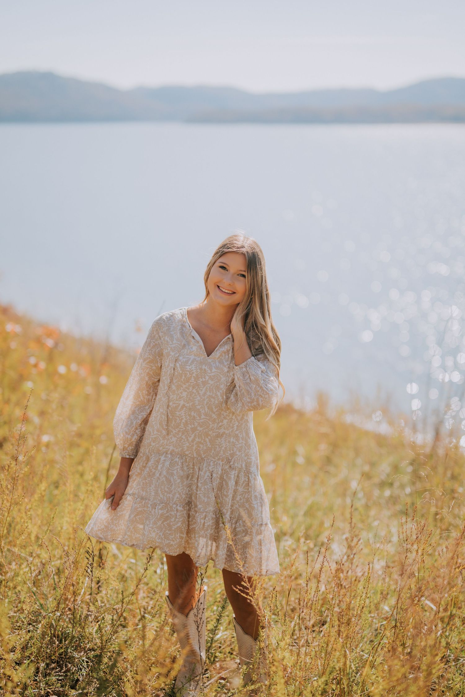 Portrait session in a lakeside meadow with tall grass and mountain views.