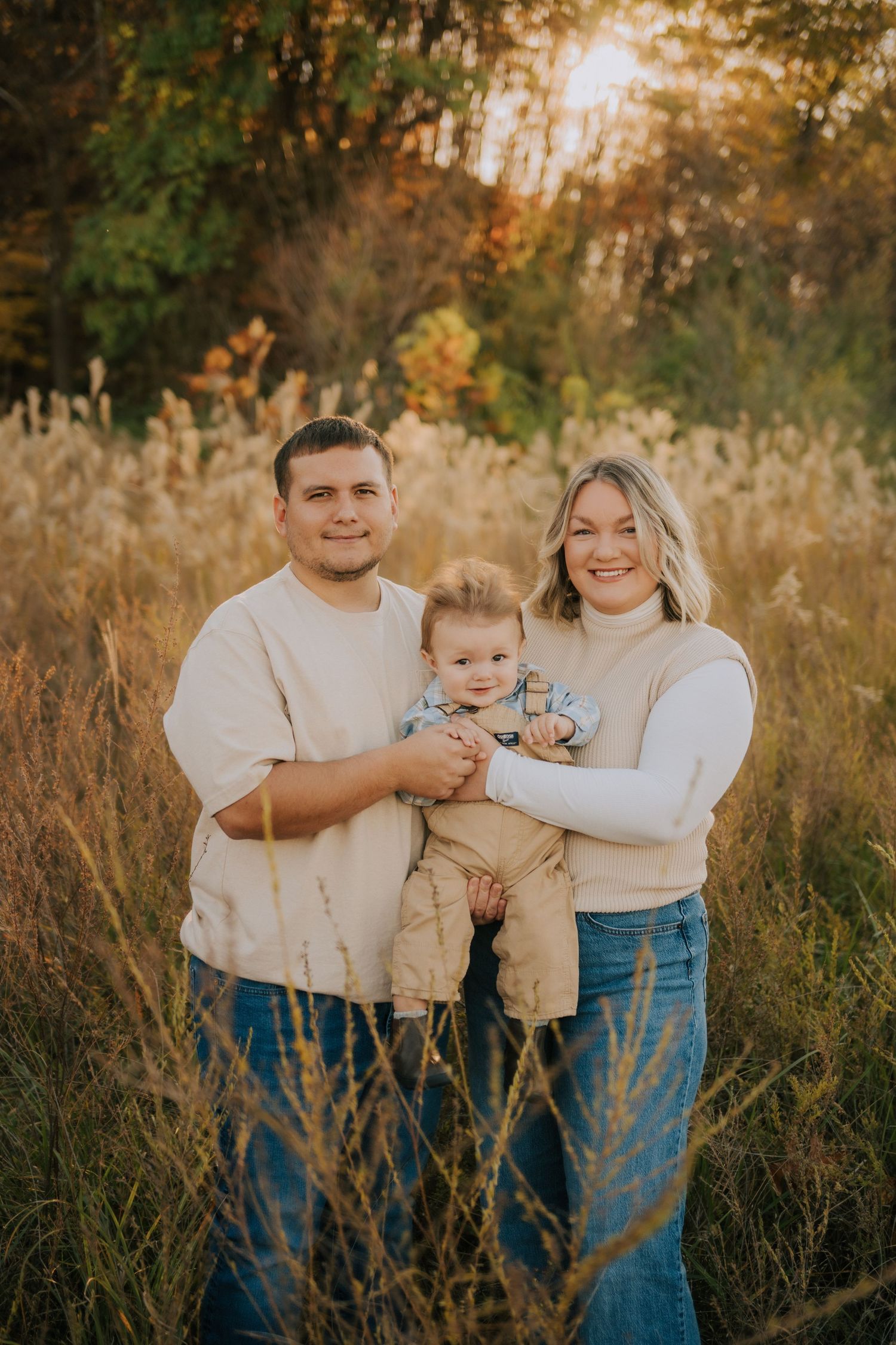 Sunset family portrait in matching white shirts and jeans among tall grass.