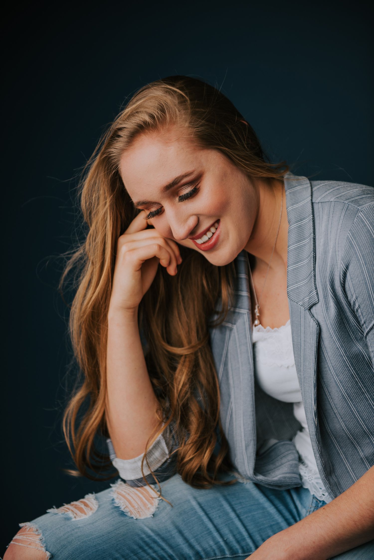 Professional portrait in grey blazer against dark background with candid expressions.