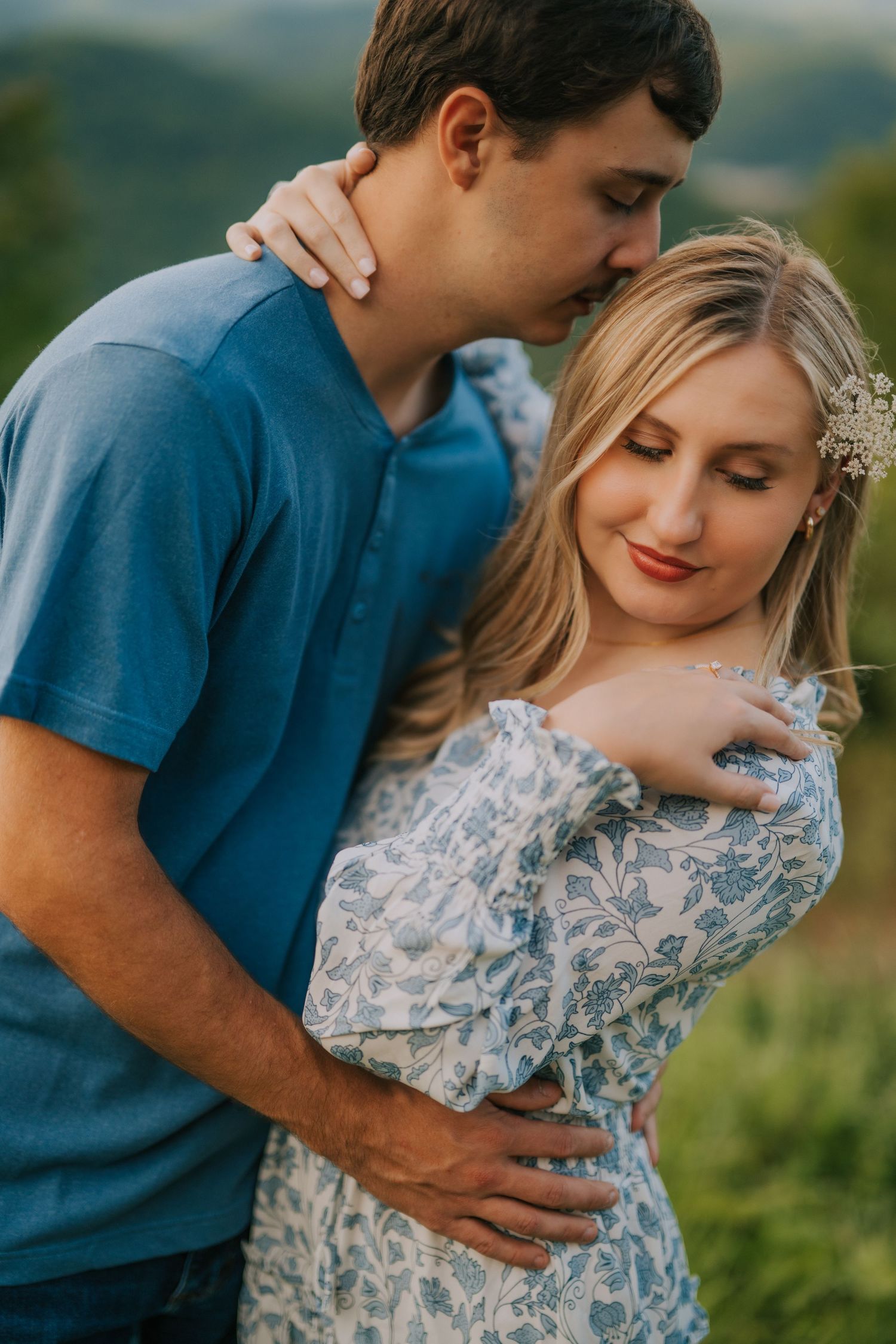 Intimate couple portrait in a floral dress against scenic mountain backdrop.