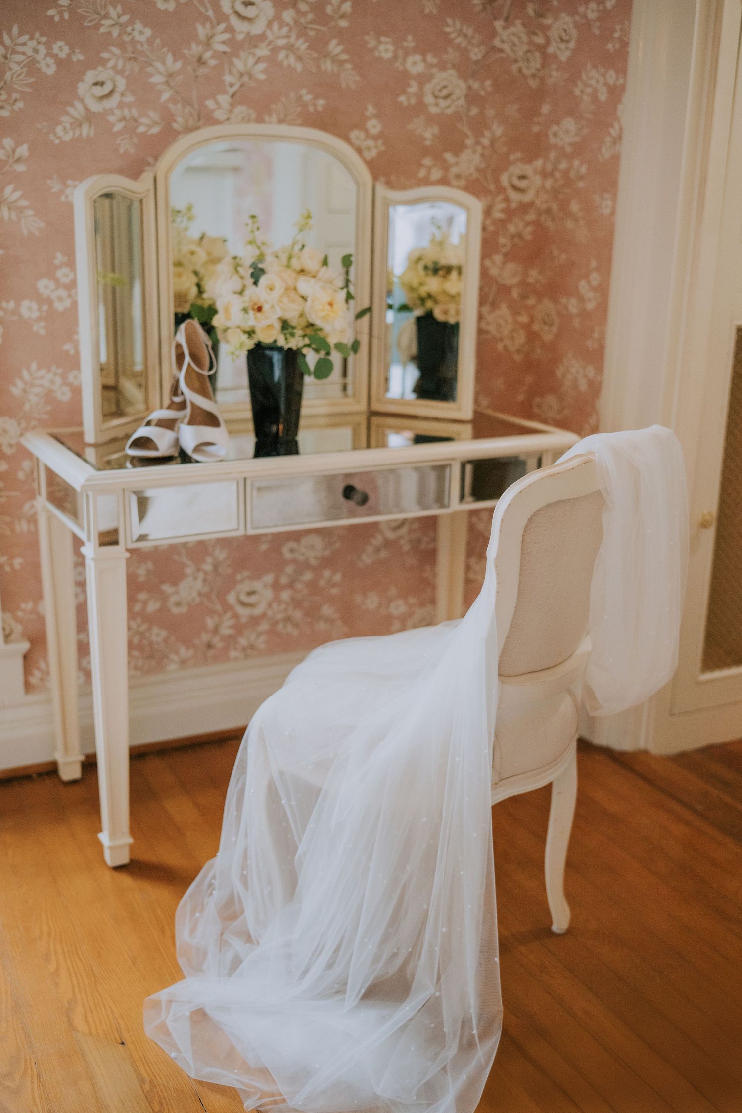 An elegant bridal preparation room with vintage furniture and flowing white fabric.