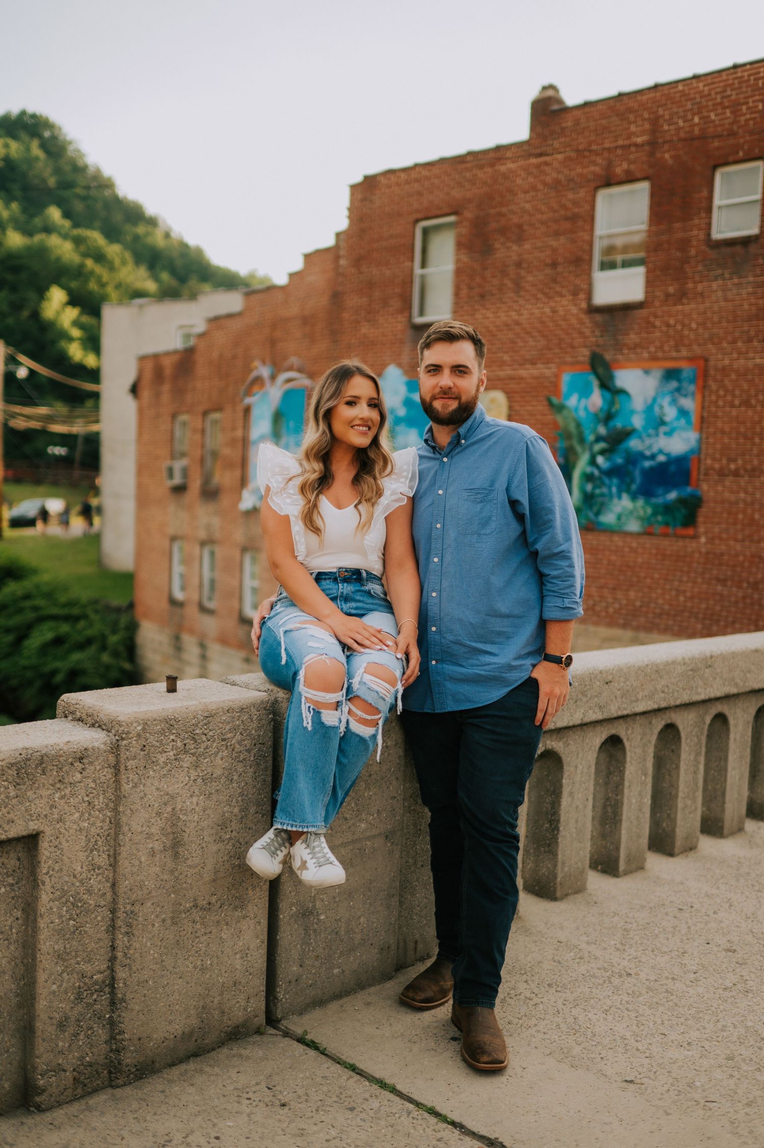 A family poses together on a concrete walkway near a brick building with blue artwork.